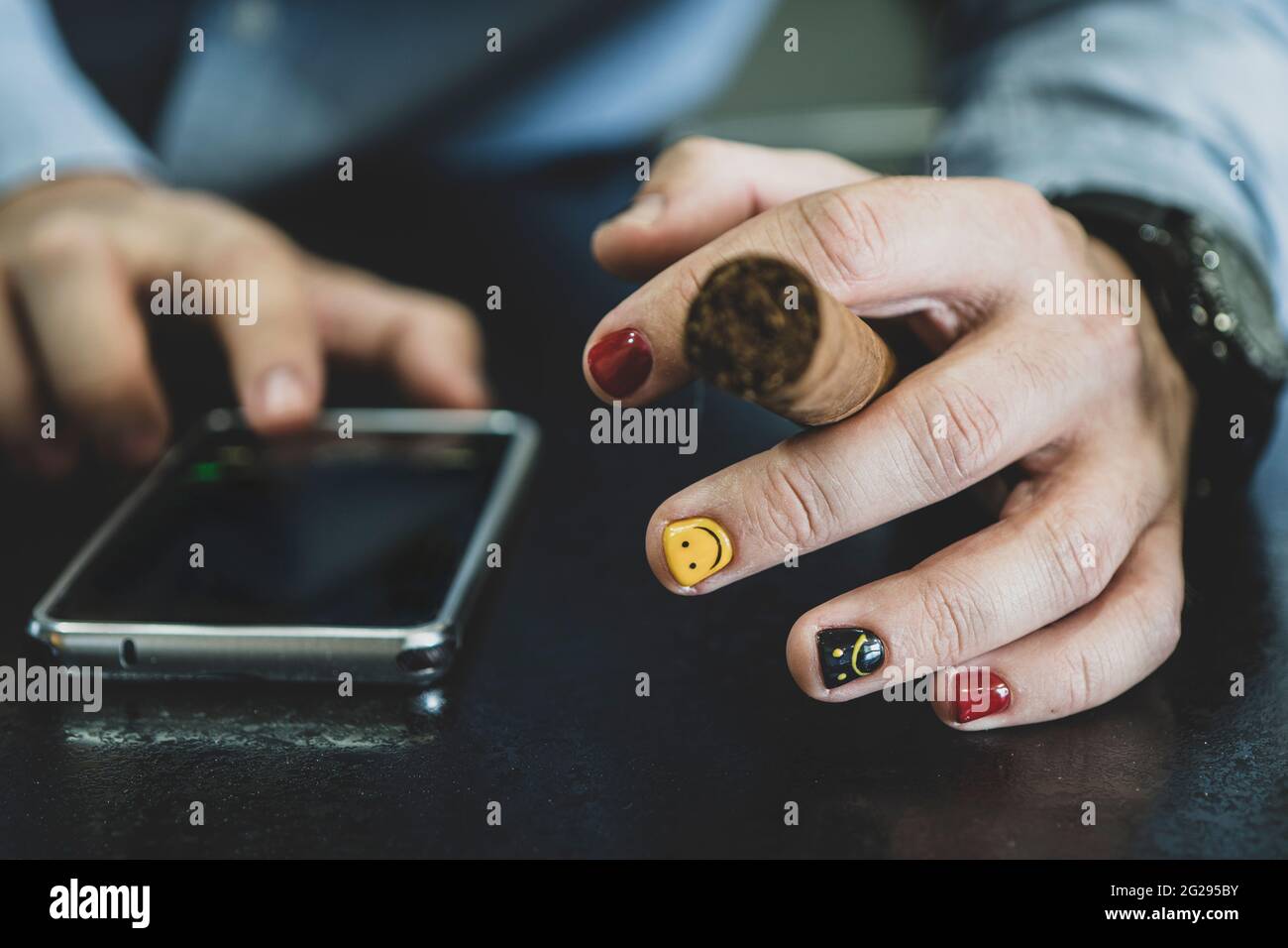 Close up of gentleman holding modern smartphone and smokes a cigar 