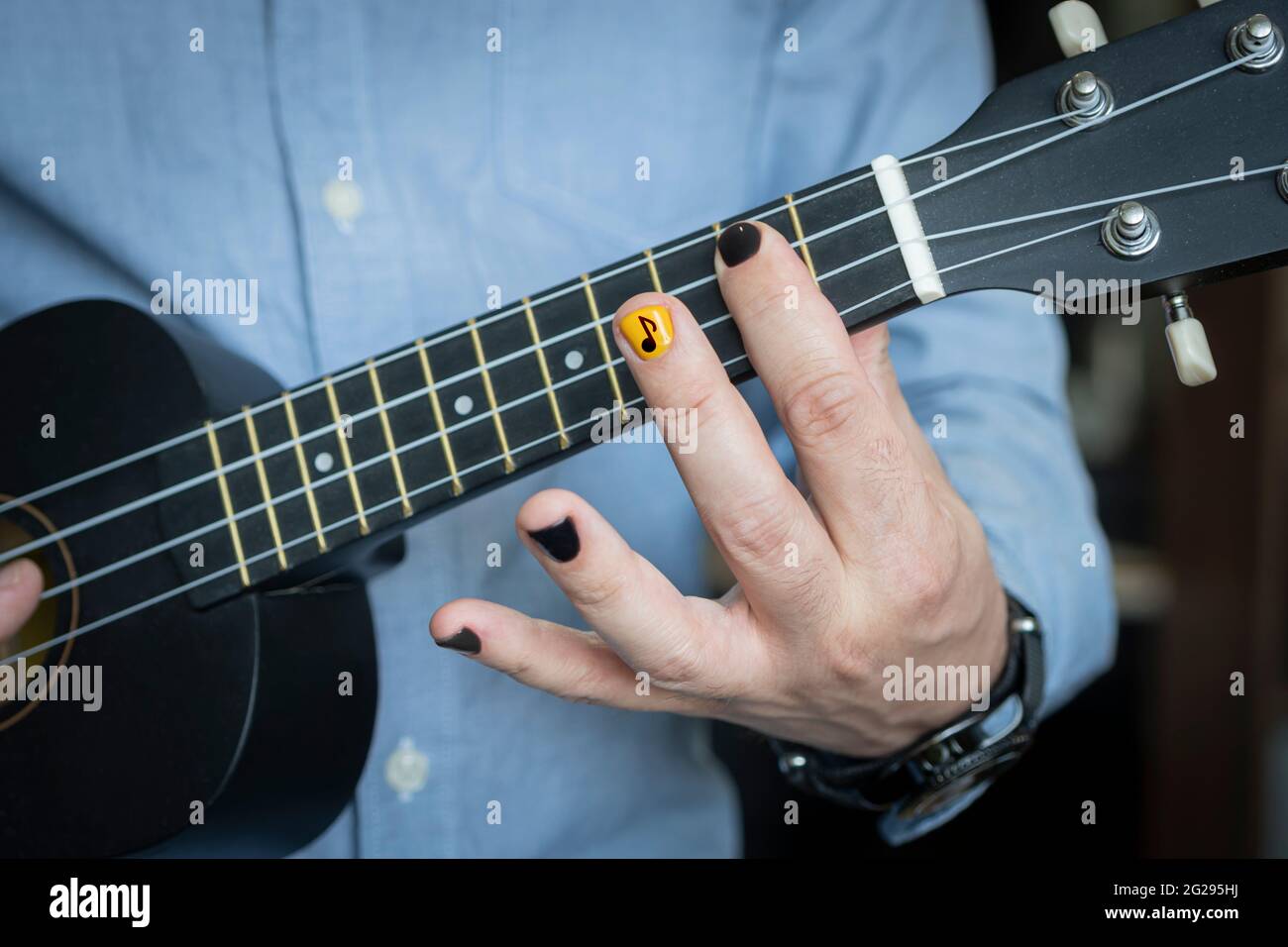 Rock musician plays on hawaiian guitar. Practicing and having fun alone.  Young musician in room. reggae guitar. An informal young guy holds a  musical Stock Photo - Alamy