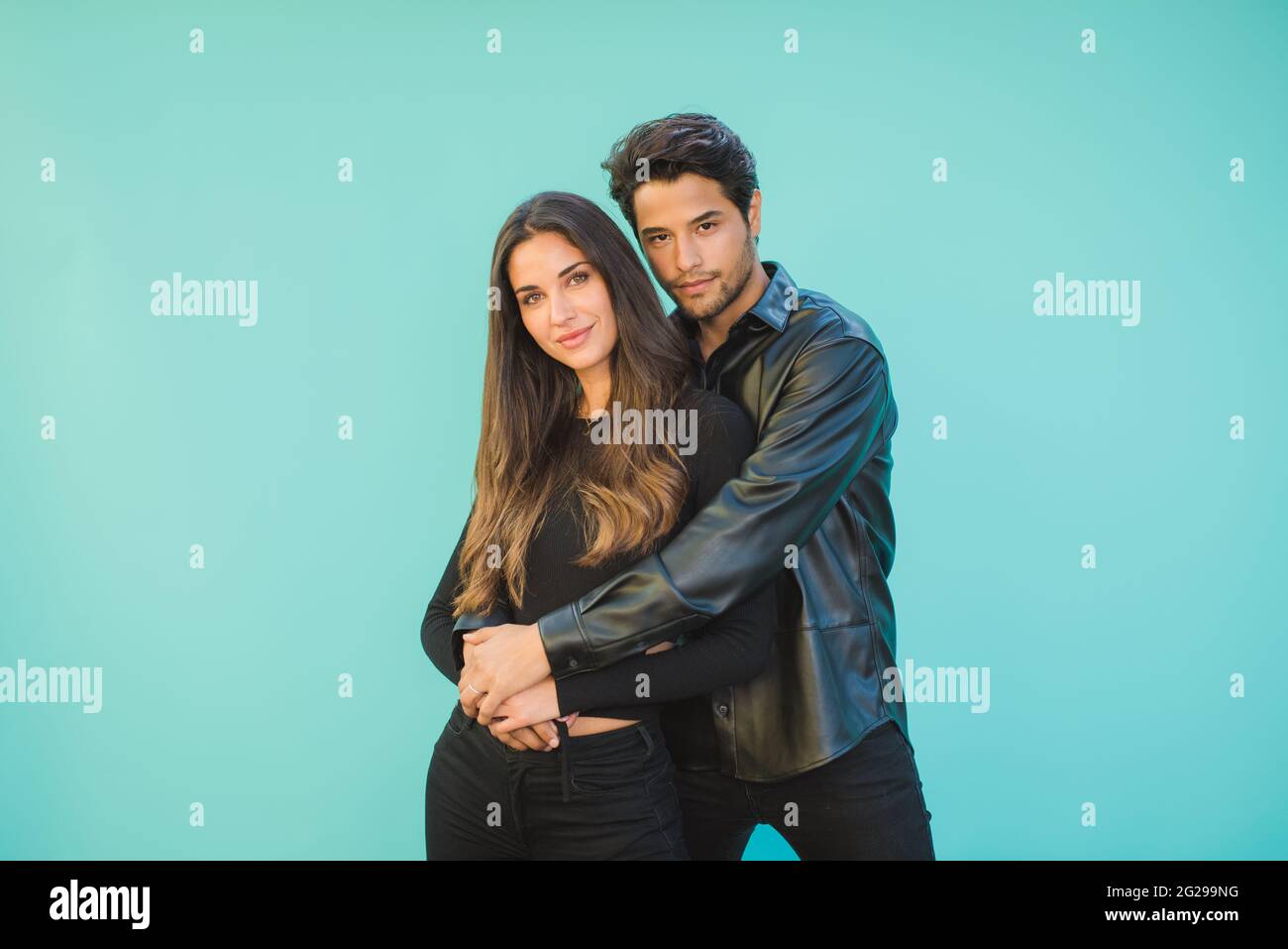 Smiling young couple embracing on aquamarine background Stock Photo