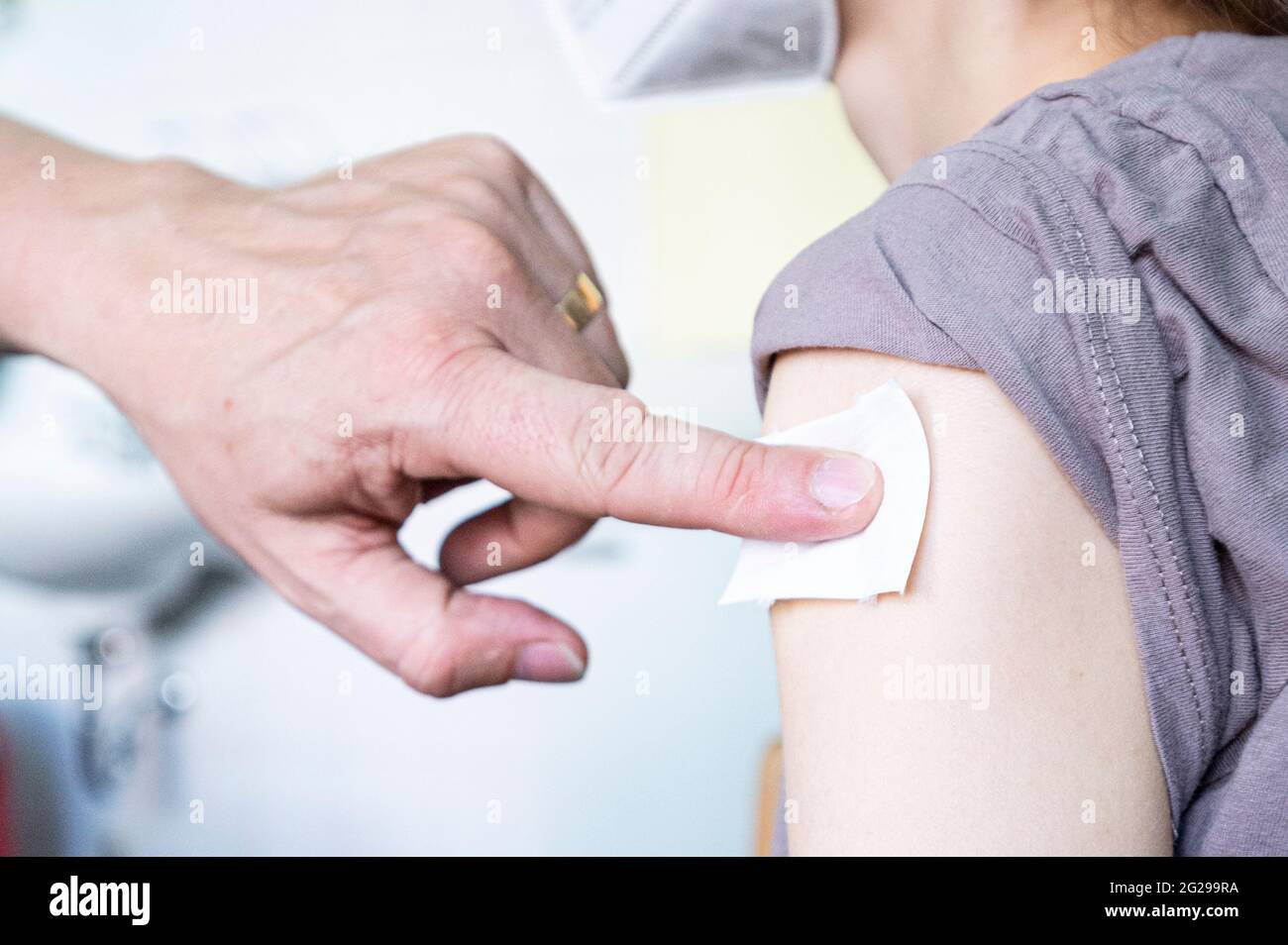 09 June 2021, Berlin: A pediatrician presses a swab to the site where a young woman was inoculated with Biontech/Pfizer's Comirnaty corona vaccine. Photo: Fabian Sommer/dpa Stock Photo