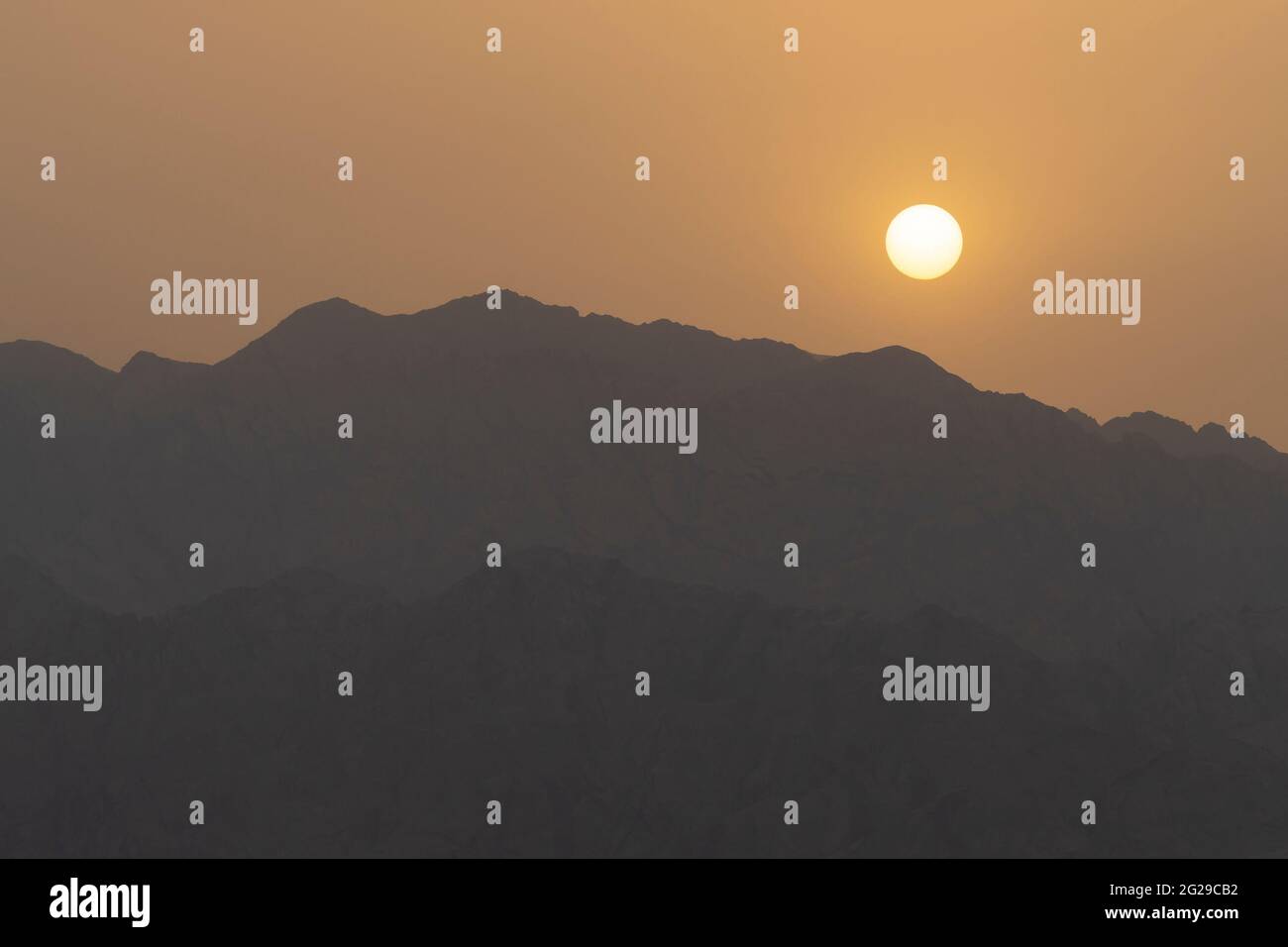 A hazy sunrise over the Edom mountain ridges, Jordan, as viewed from Israel. Stock Photo