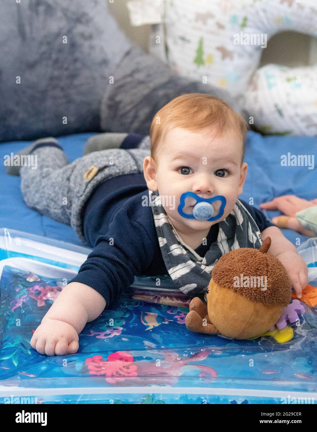 Baby boy laying on stomach sucking on pacifier. Stock Photo