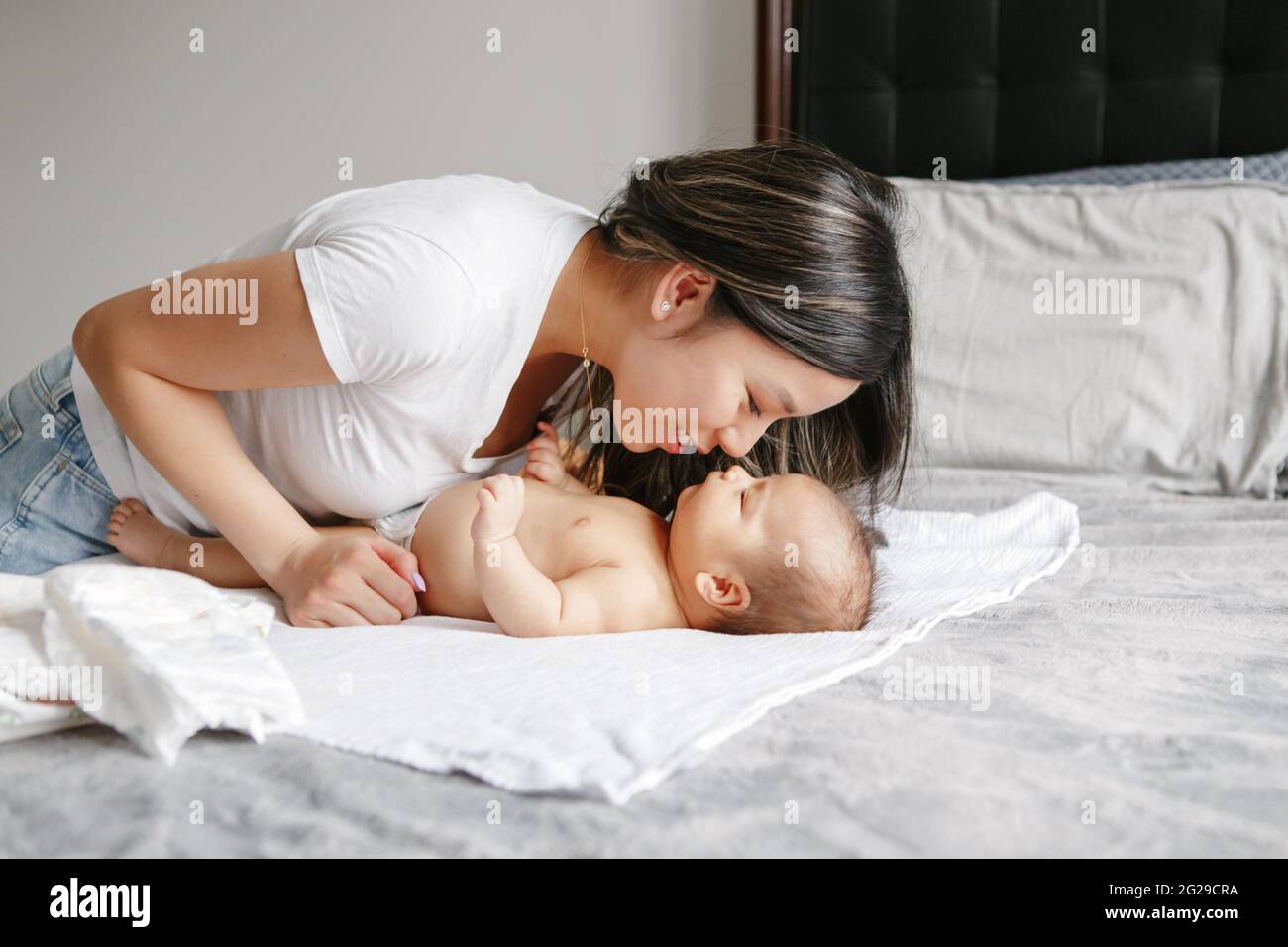 Chinese Asian busy mother changing diaper clothes for newborn at home Stock Photo