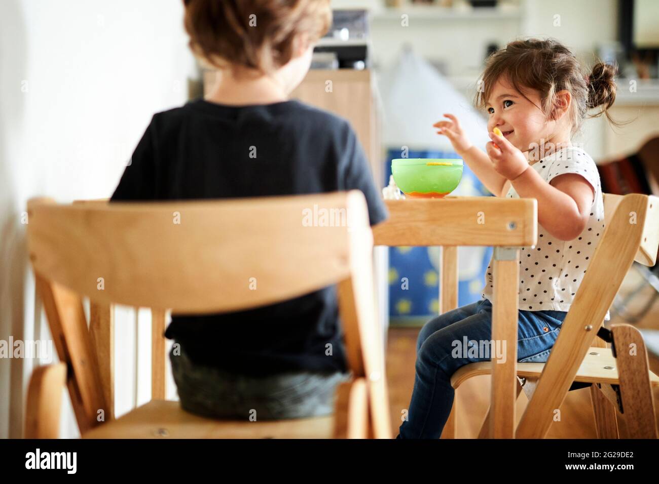 Cute girl looking at brother while having breakfast at home Stock Photo
