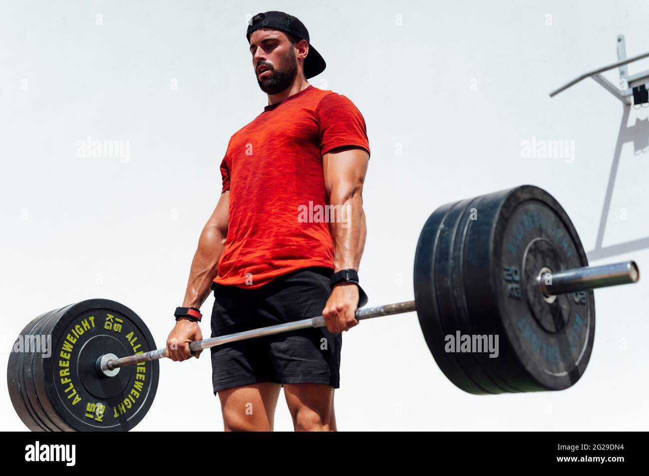 Weightlifting fitness man bodybuilding or powerlifting at outdoor gym. Bodybuilder strength training lifting barbell weights doing deadlift exercise. Stock Photo