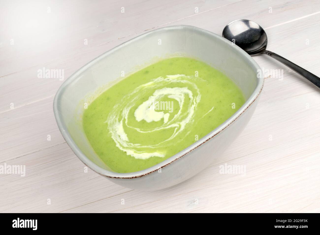 A bowl of Leek & Potato Soup on a white wooden table. Stock Photo