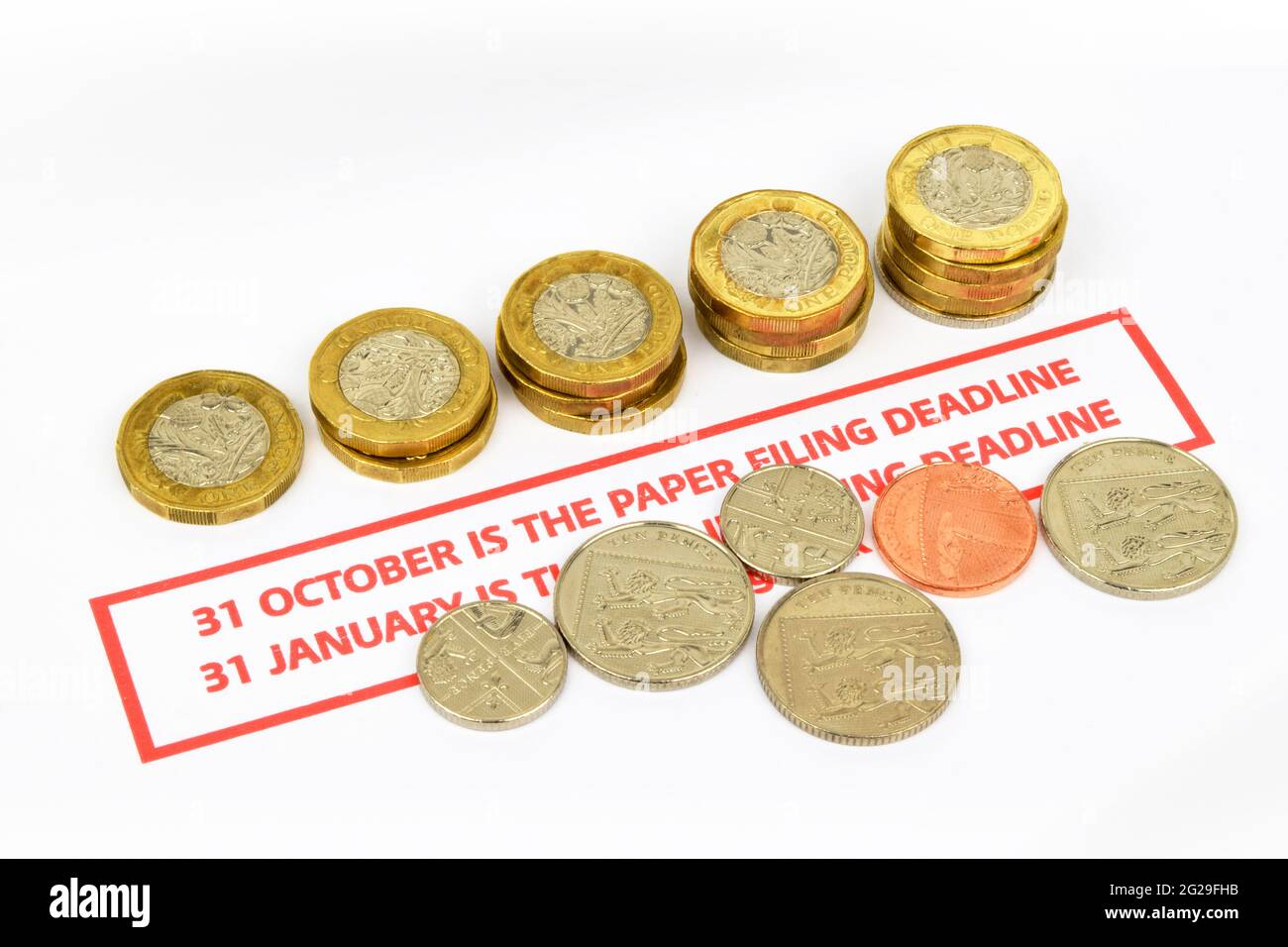 Uk tax return paper filing deadline reminder. A still life  including a deadline reminder in red, coins and a pen. Stock Photo