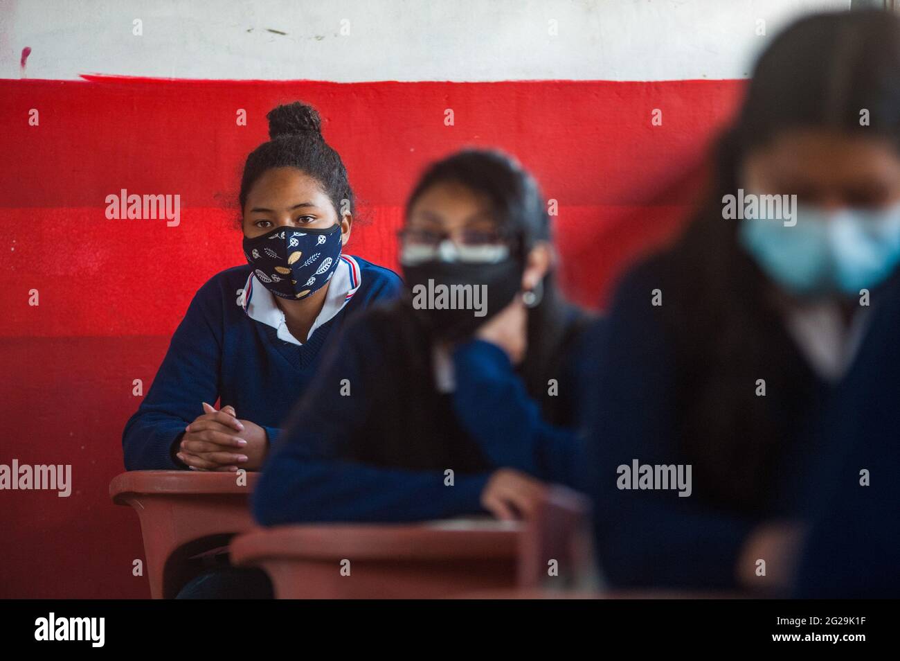 Students wearing face masks sit in a classroom at the Agricultural Technical School Eduardo Salazar Gomez. Ecuador authorized the return to voluntary classes in private and Fiscal institutions, this is the case of the Agricultural Technical School Eduardo Salazar Gomez in the Pifo parish located in the Northwest of the Capital Quito, in this establishment around 43 students of 1st, 2nd grade have entered and 3rd of Baccalaureate in each classroom the total capacity is up to 12 students respecting social distance, this initiative responds to the need of many of these young people to be able to Stock Photo