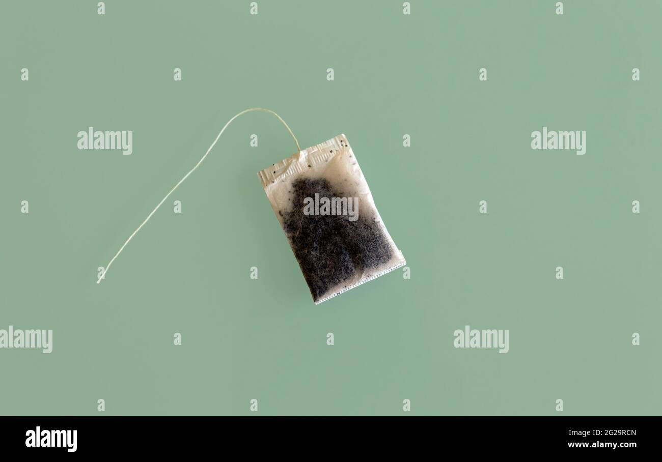 Top view of A dry unused teabag with no label card isolated on green glass surface Stock Photo