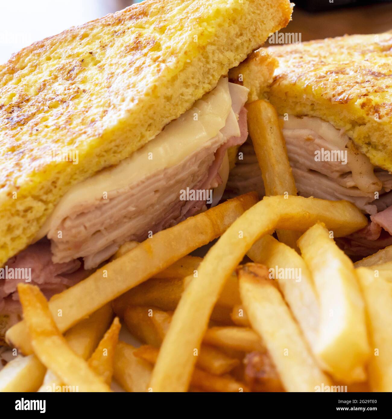 A monte cristo sandwich sits on a white plate at a diner.  Served with French fries. Stock Photo