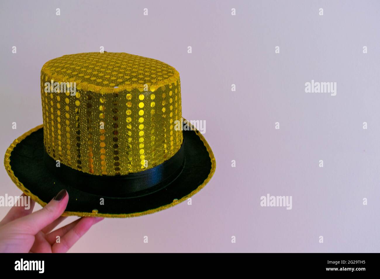 Magic gold yellow sequined top hat on isolated background with space for copy text. Magicians performance show, magic tricks concept background. Fancy Stock Photo