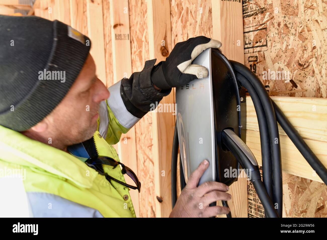 Electrician installing Tesla Charger mounted inside garage at private residence used for recharging Tesla electric vehicles, Browntown WI, USA Stock Photo
