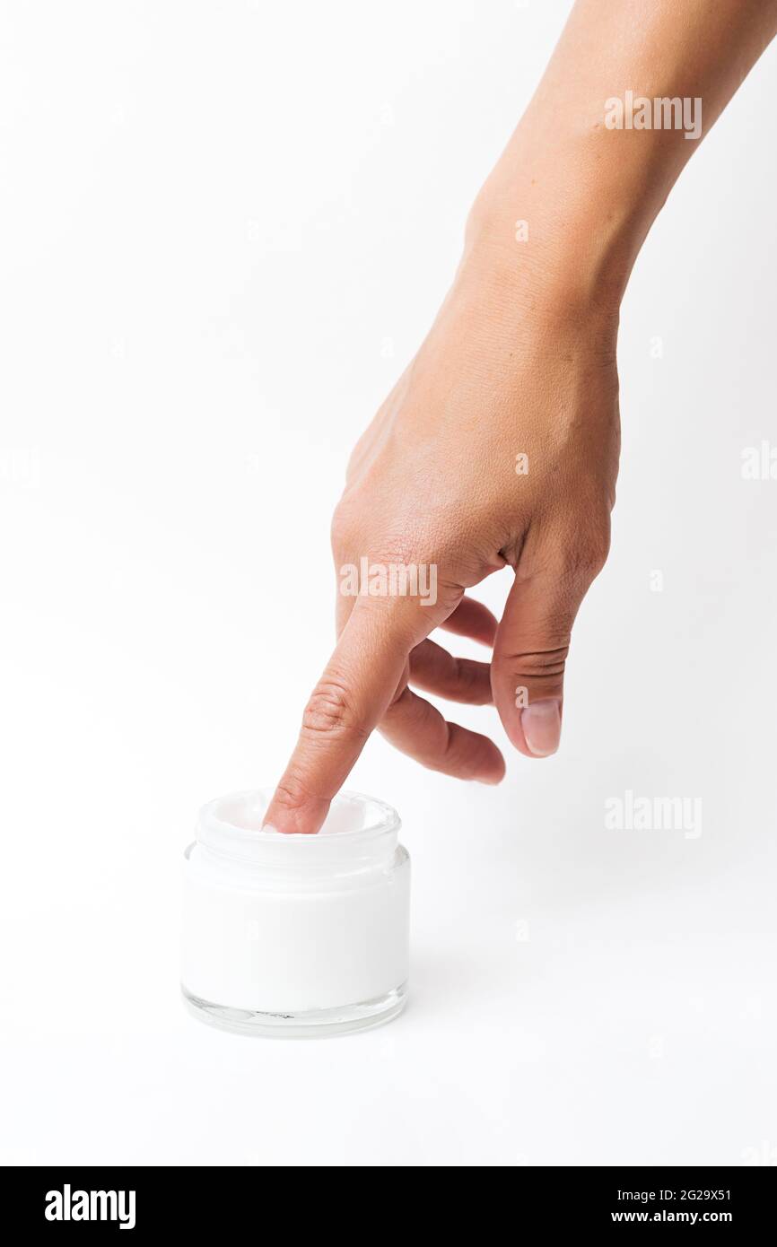 Woman moisturizing skin hand with cosmetic cream. Female hand touch glass jar of cream lotion. Beauty concept minimalism style. Stock Photo