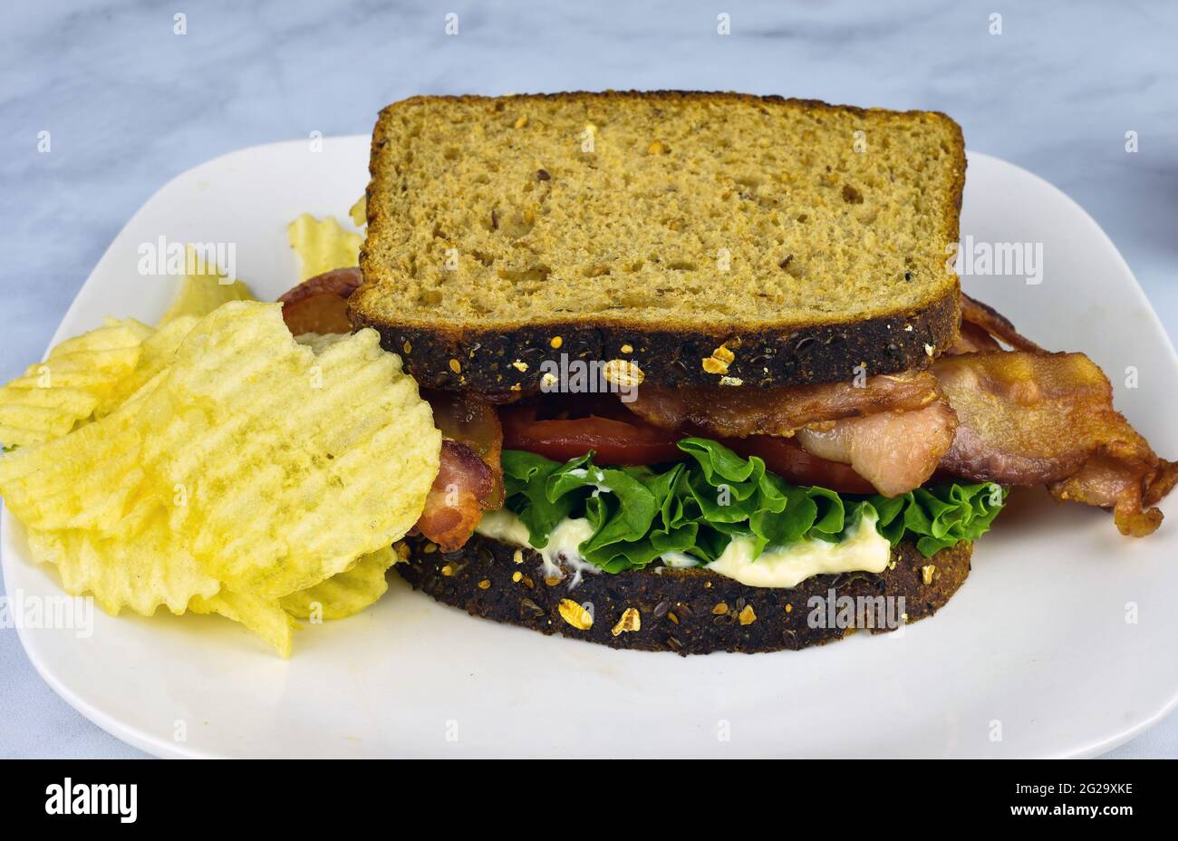 blt sandwich on whole wheat bread with a side of potato chips Stock