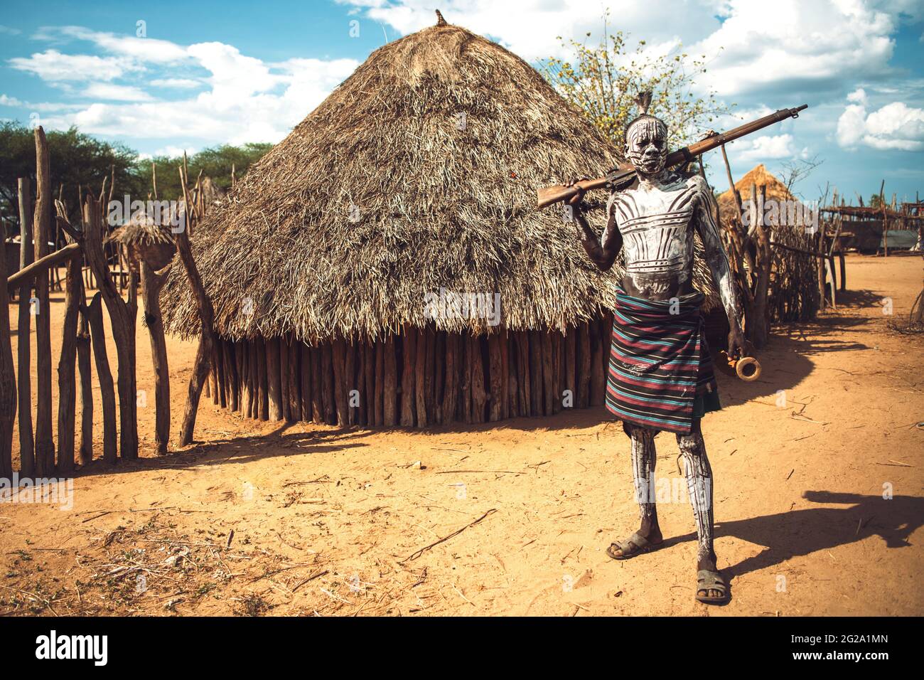 man with painted body holding a shotgun in Karo tribe village. Omo Valley, Ethiopia Stock Photo