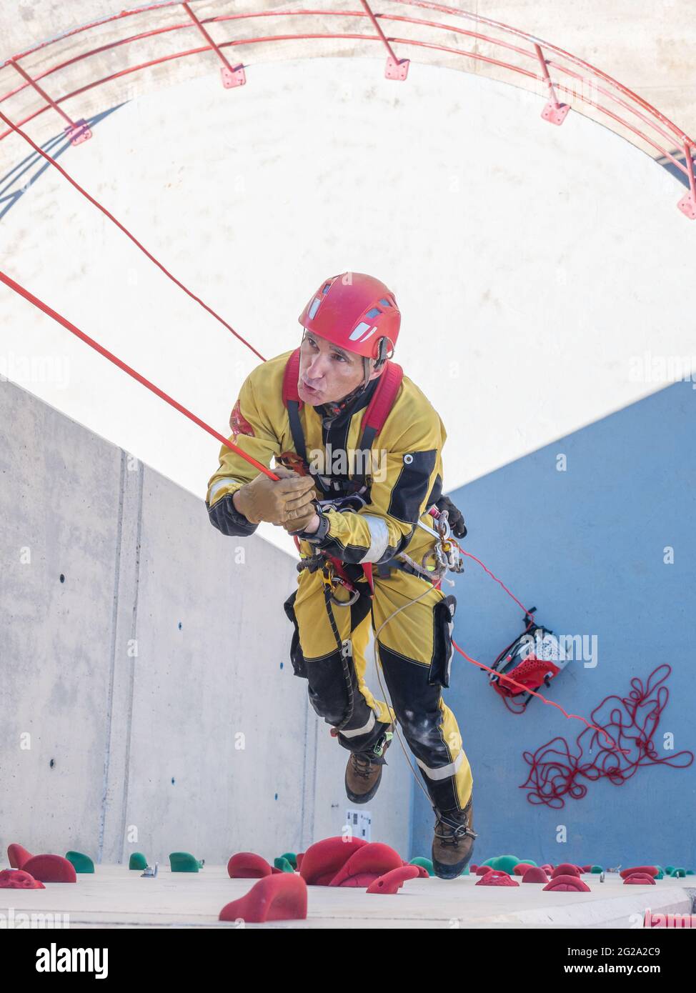 Professional fireman climber in uniform hanging on ropes while training ...