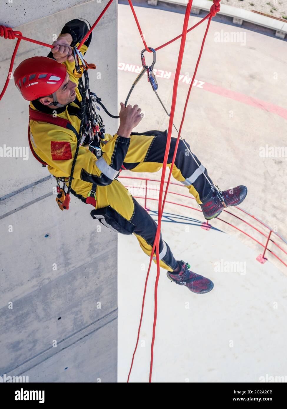 Professional fireman climber in uniform hanging on ropes while training ...