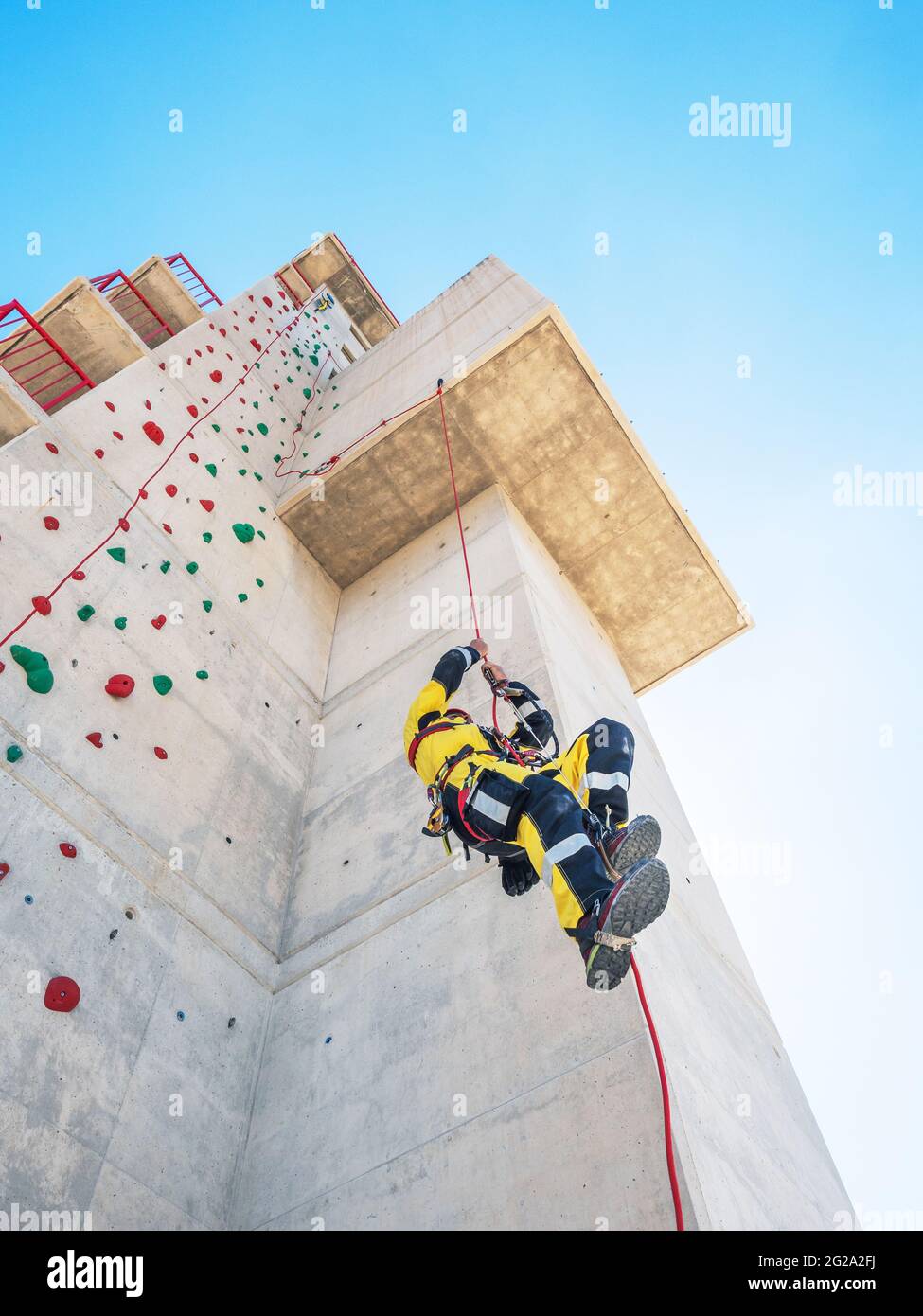 from below Professional firemen climbers in uniform hanging on ropes ...
