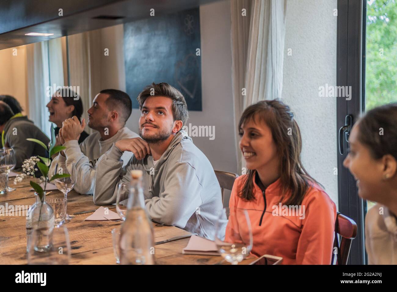 Smiling joyful people spending time and enjoying at table with glasses celebrating in light room Stock Photo