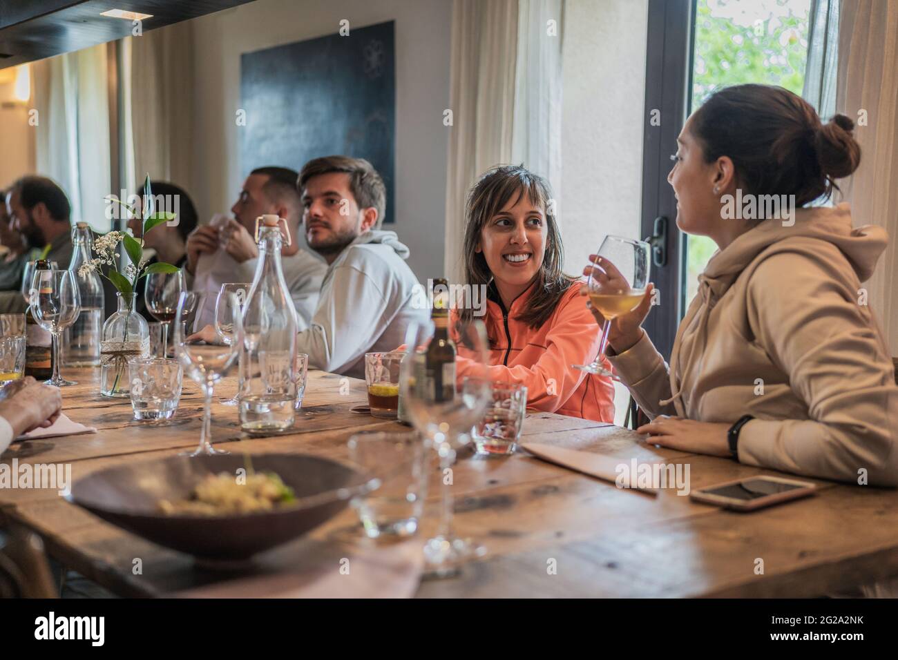 Smiling joyful people spending time and enjoying at table with glasses celebrating in light room Stock Photo