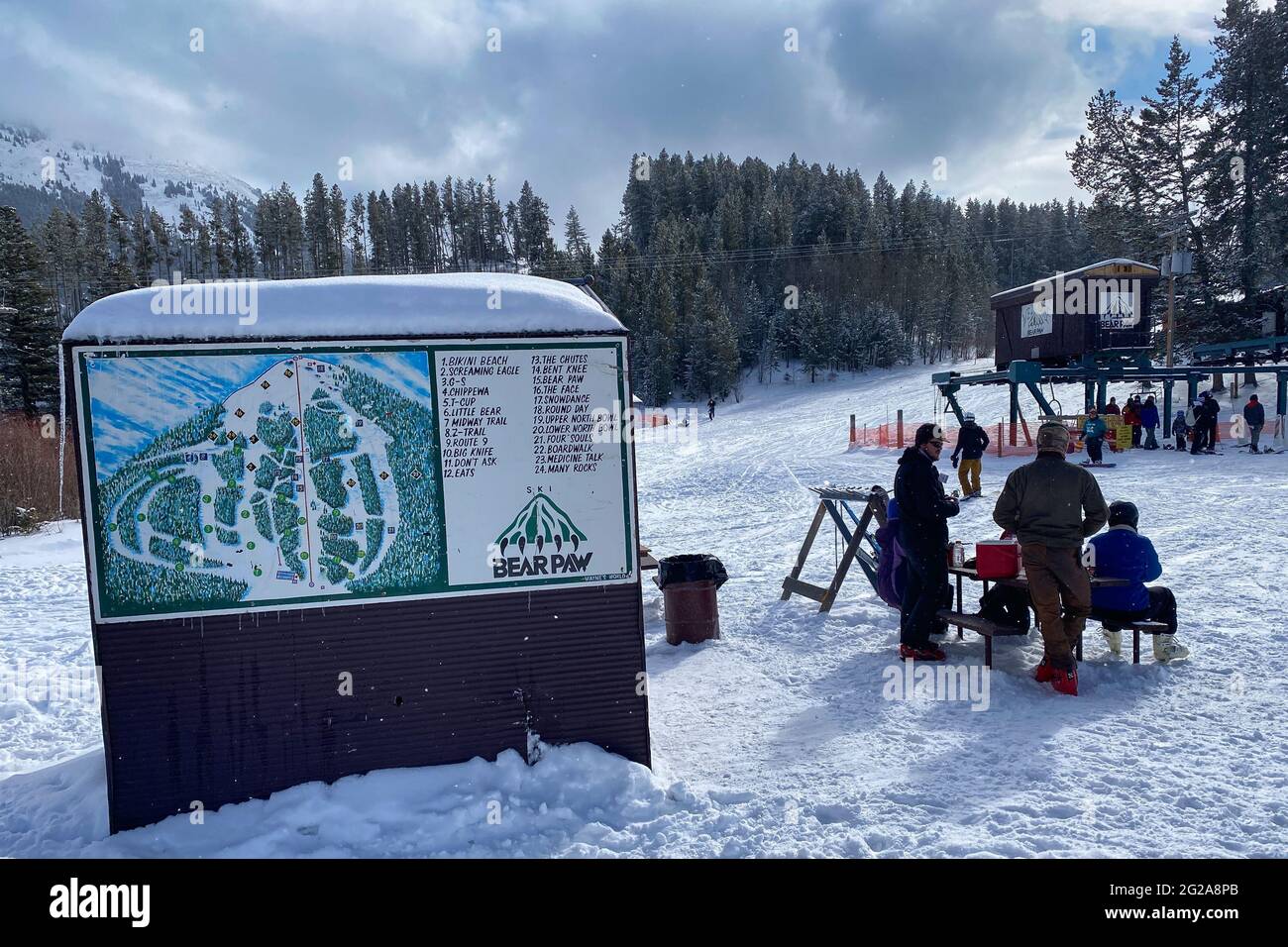 Trail map with skiers and chairlift in the background at Bear Paw Ski