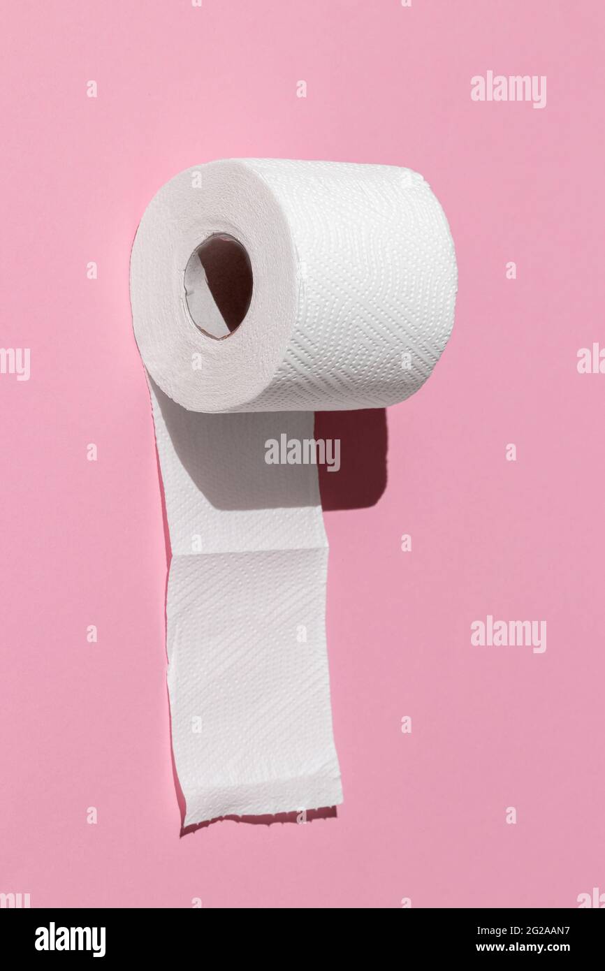 roll of a white toilet paper isolated on a pink background close-up. hard shadows from the sun at noon Stock Photo