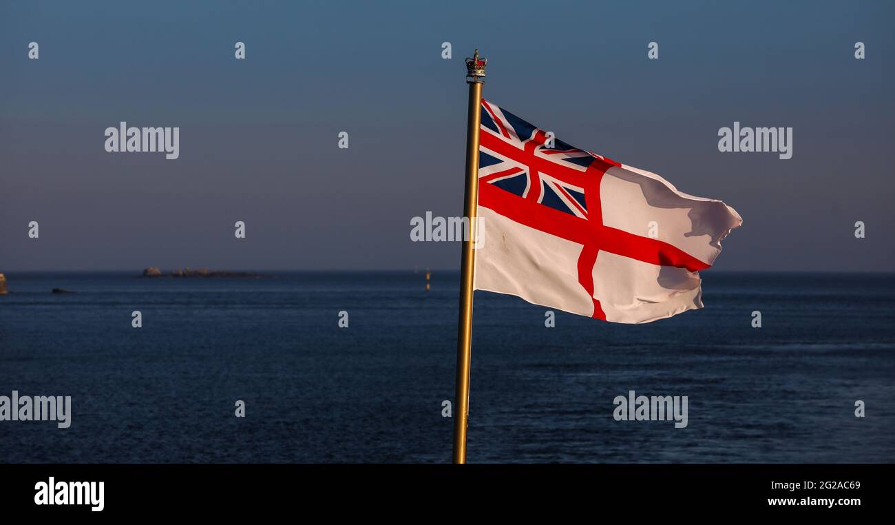 The flag of the British Royal Navy the White Ensign being flown from the ensign staff of a British warship Stock Photo