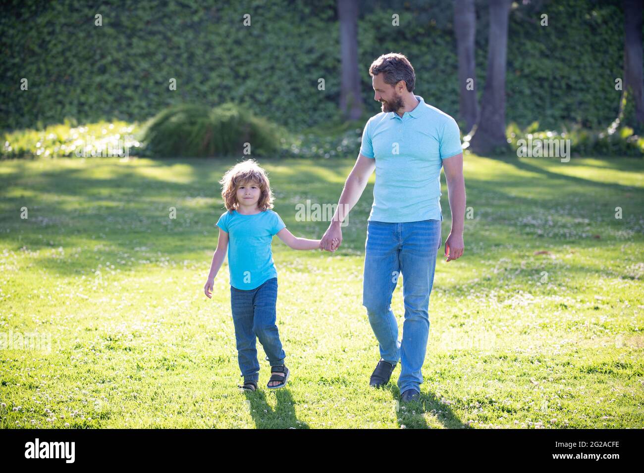happy family value. childhood and parenthood. parent leads little child boy on grass. Stock Photo