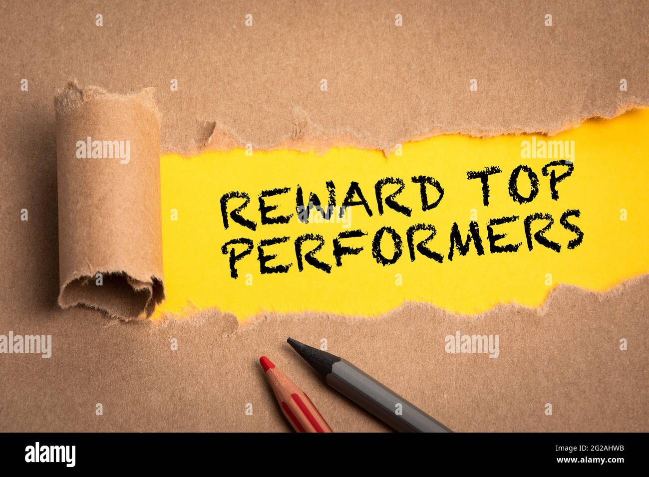 Reward top performers. Torn cardboard on a yellow background. Stock Photo