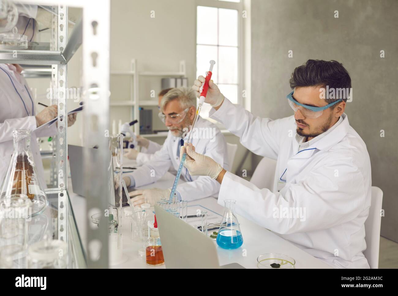 Man scientist putting medical chemicals sample in test tube at laboratory Stock Photo