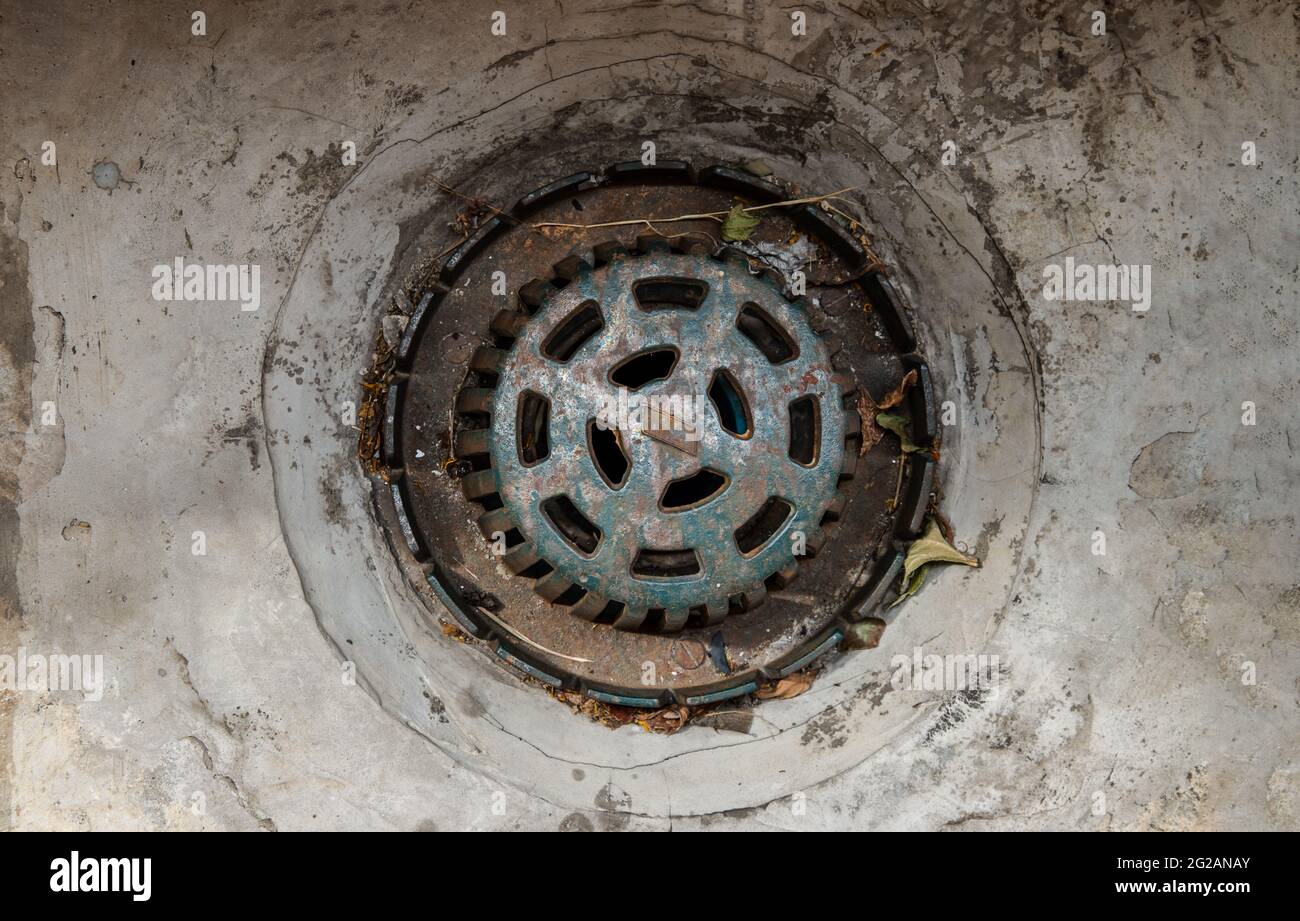 Old steel round storm drain grate on the main hole drains the water. A ...