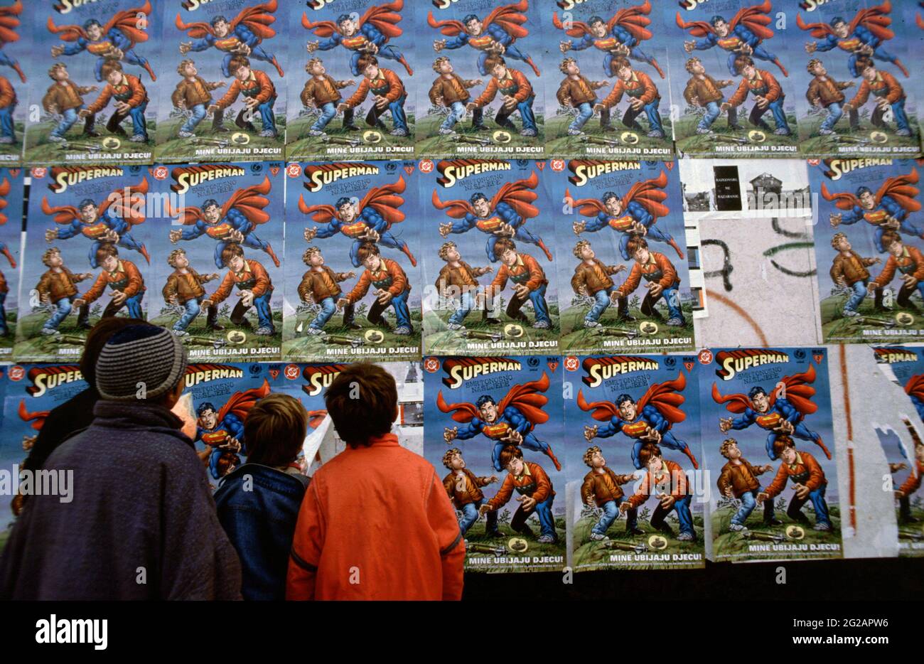 Sarajevo, Bosnia and Herzegovina. March 1997. Children in the city look at posters for 'Superman: Deadly Legacy' a special-edition 'humanitarian comic book' featuring Superman that promotes “landmine awareness' among children, particularly from countries where there are active landmines after war. The Superman comic book was published by DC Comics, the United States government, and United Nations International Children's Emergency Fund (UNICEF) in 1996. The Bosnian War, ethnically rooted war in Bosnia and Herzegovina that took place from 1992 to 1995 in Former Yugoslavia. Stock Photo