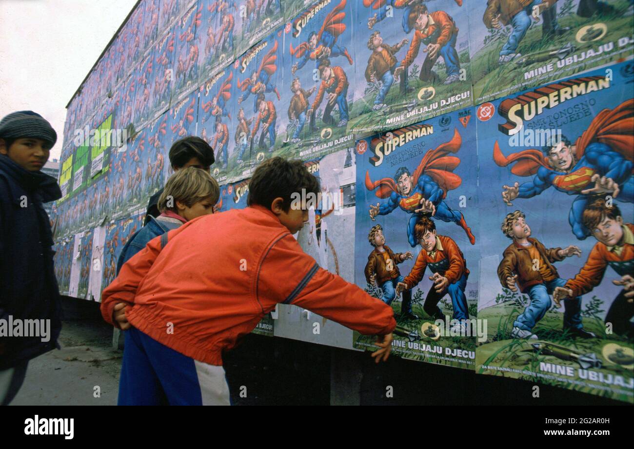 Sarajevo, Bosnia and Herzegovina. March 1997. Children in the city look at posters for 'Superman: Deadly Legacy' a special-edition 'humanitarian comic book' featuring Superman that promotes “landmine awareness' among children, particularly from countries where there are active landmines after war. The Superman comic book was published by DC Comics, the United States government, and United Nations International Children's Emergency Fund (UNICEF) in 1996. The Bosnian War, ethnically rooted war in Bosnia and Herzegovina that took place from 1992 to 1995 in Former Yugoslavia. Stock Photo