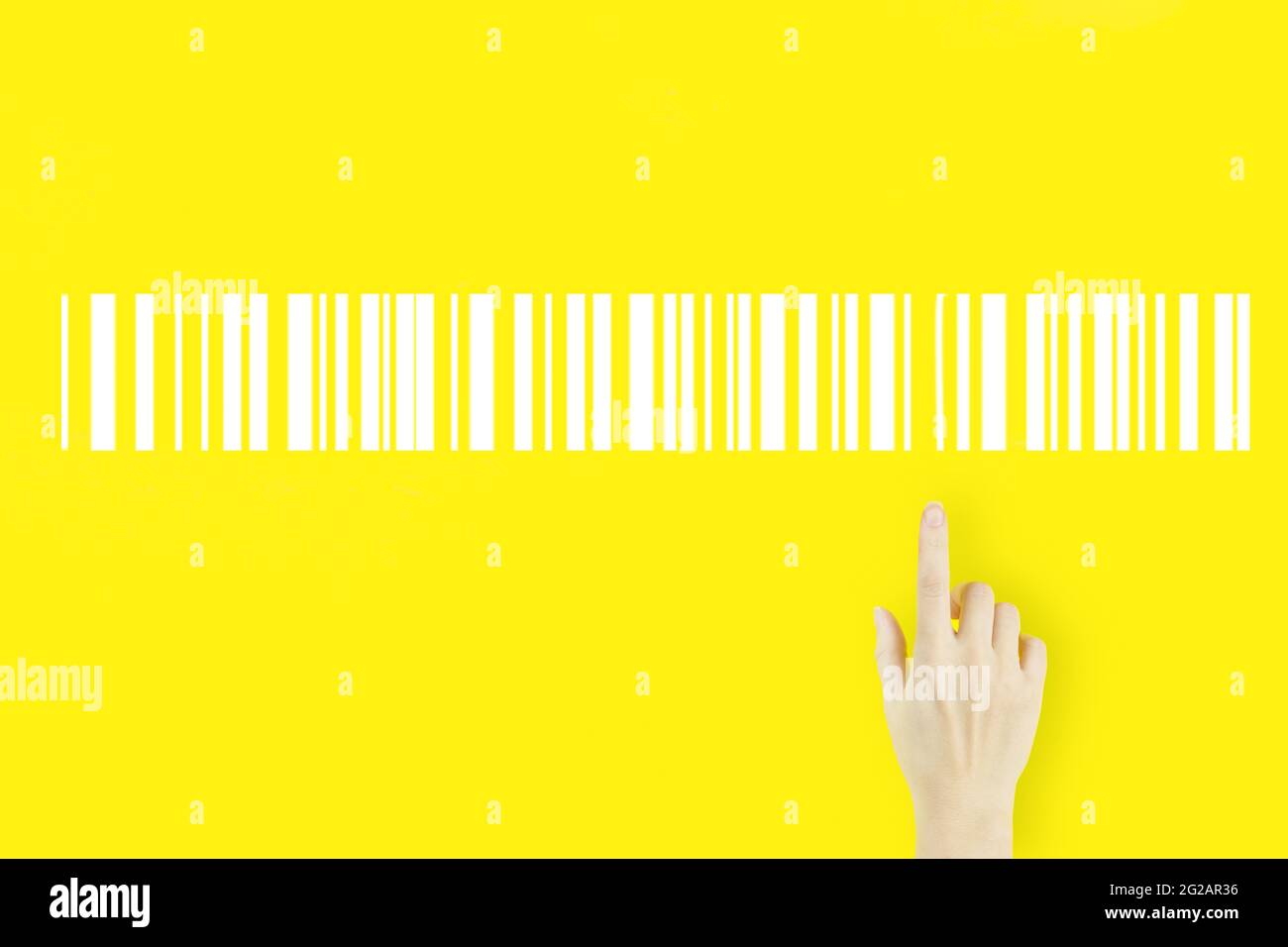 Warehouse and logistics concept. Young woman's hand pointing finger with hologram Bar Code Price Tag on yellow background. Inventory Logistics Product Stock Photo