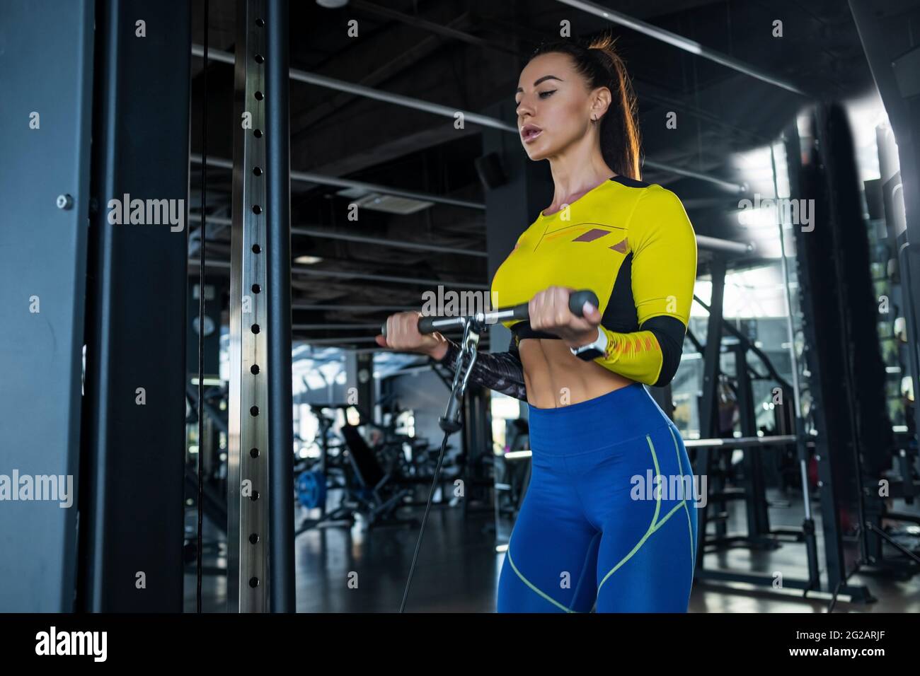 Fit doing bicep exercises on cable crossover at gym Stock