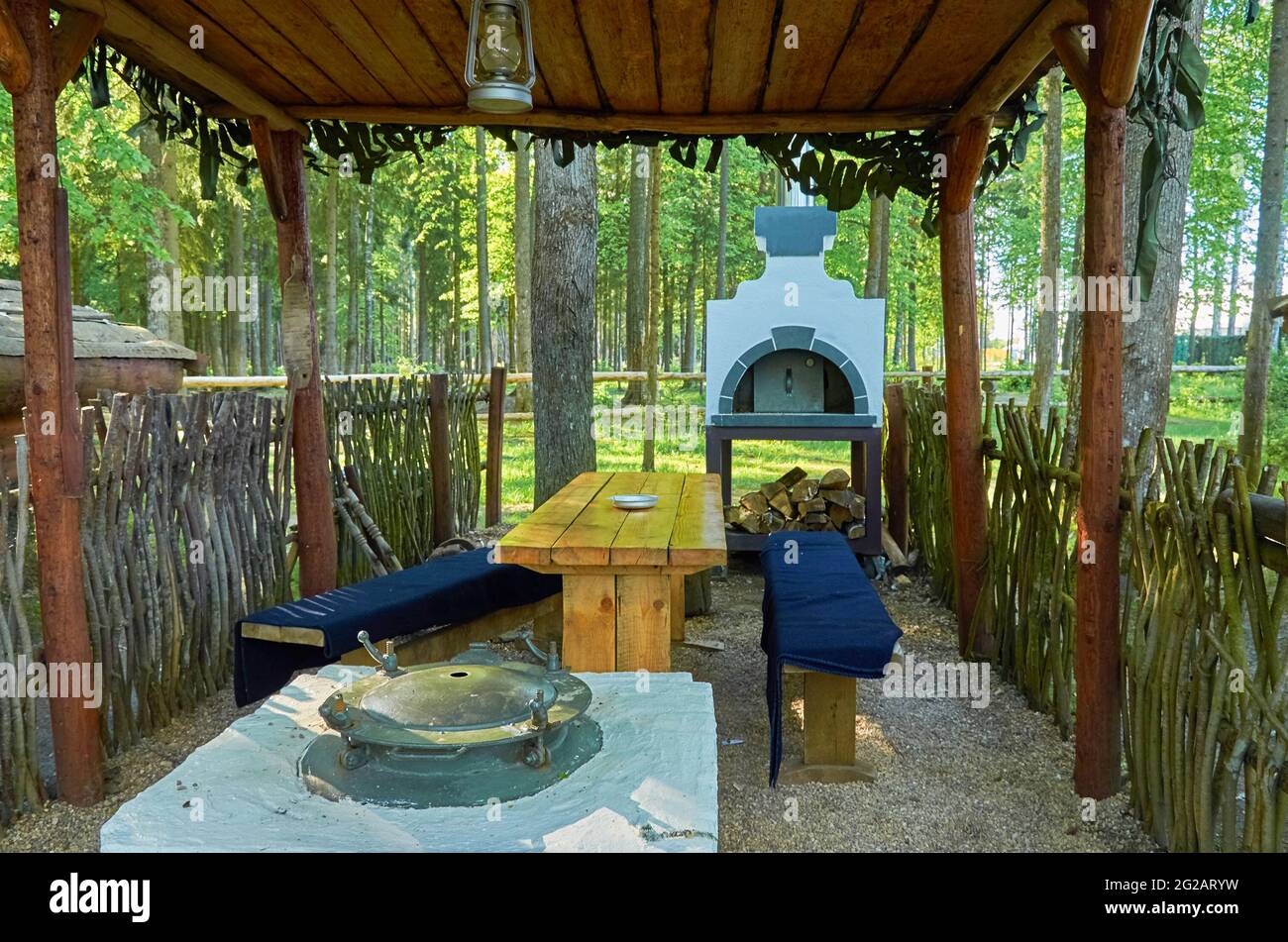 Summer kitchen with two stoves, wooden table and benches under a wooden