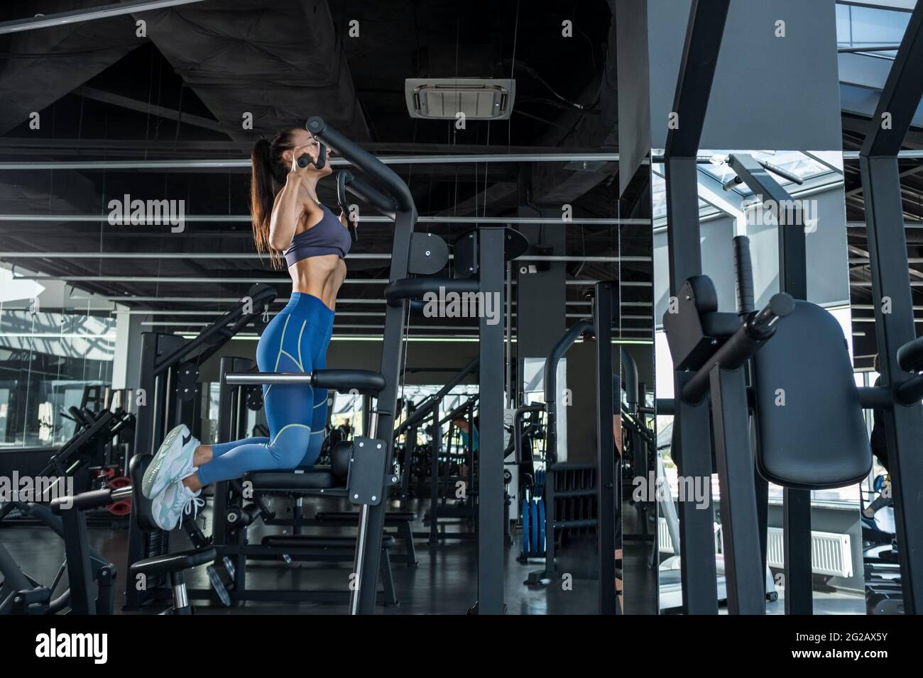 Concentrated athletic girl pulling up on machine at gym Stock Photo