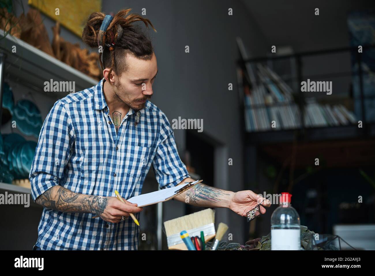 Bearded young man with clipboard working in workshop Stock Photo