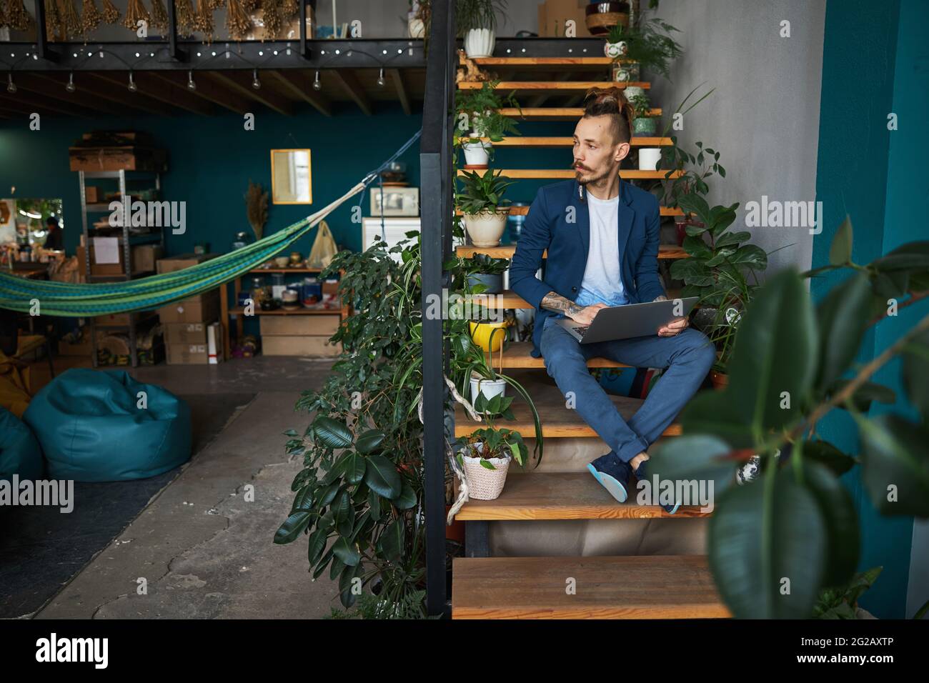 Handsome young man sitting on steps and using laptop Stock Photo - Alamy