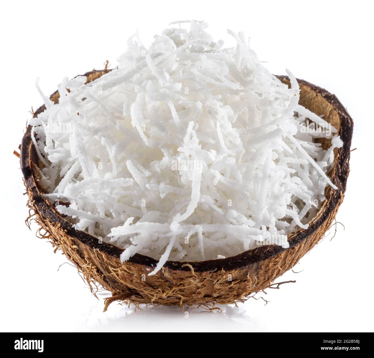 Shredded coconut flakes in the piece of coconut shell isolated on white background. Close-up. Stock Photo