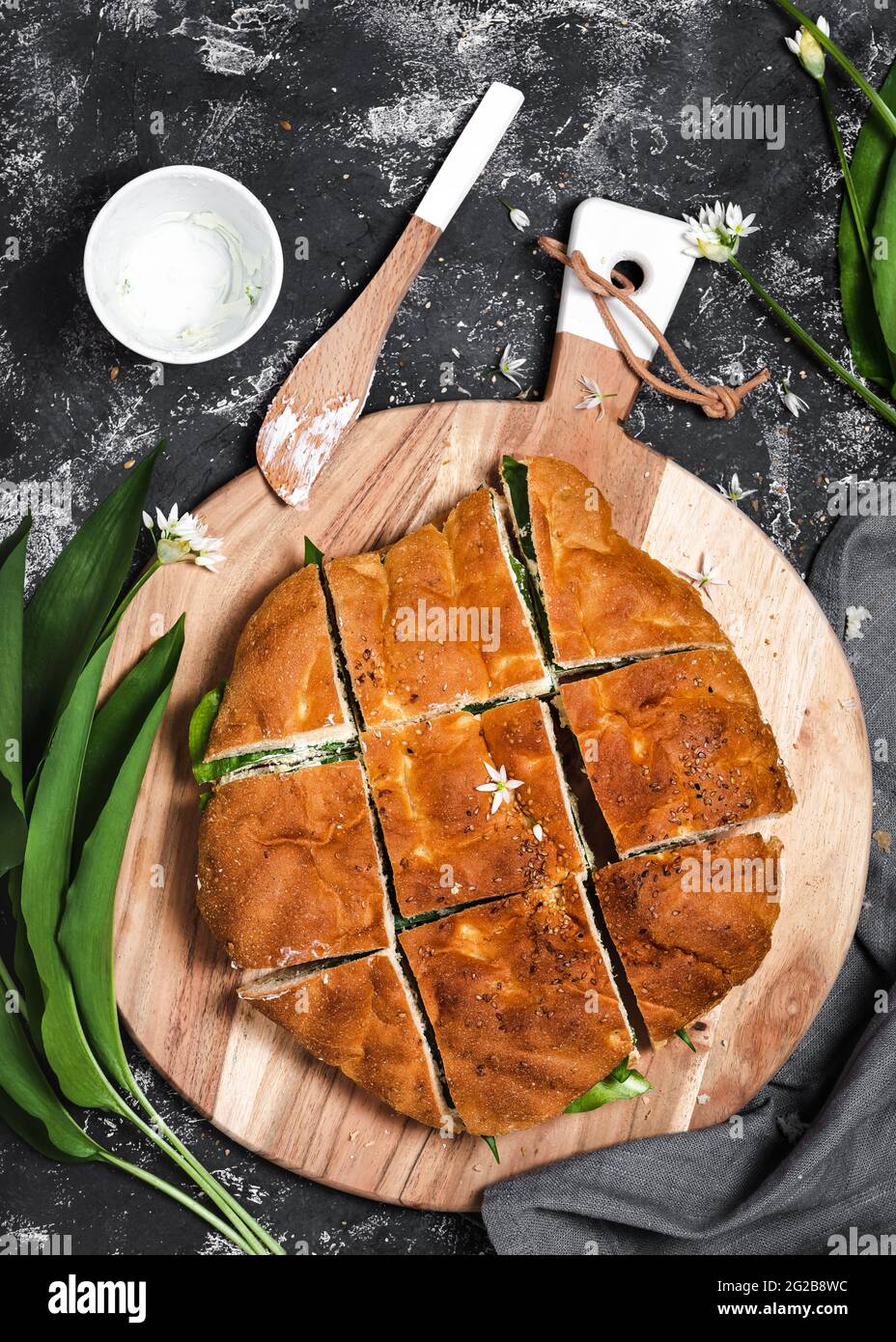 Making vegetarian sandwiches with flatbread, cheese dip and and fresh wild garlic leaves filling