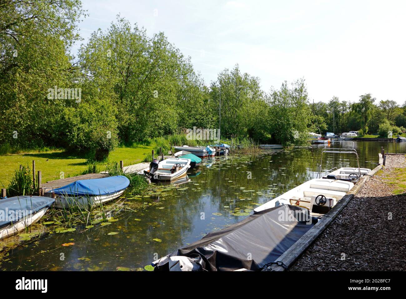 Small boats moored along a small dyke on the Norfolk Broads at Pennygate Staithe, Barton Turf, Norfolk, England, United Kingdom. Stock Photo
