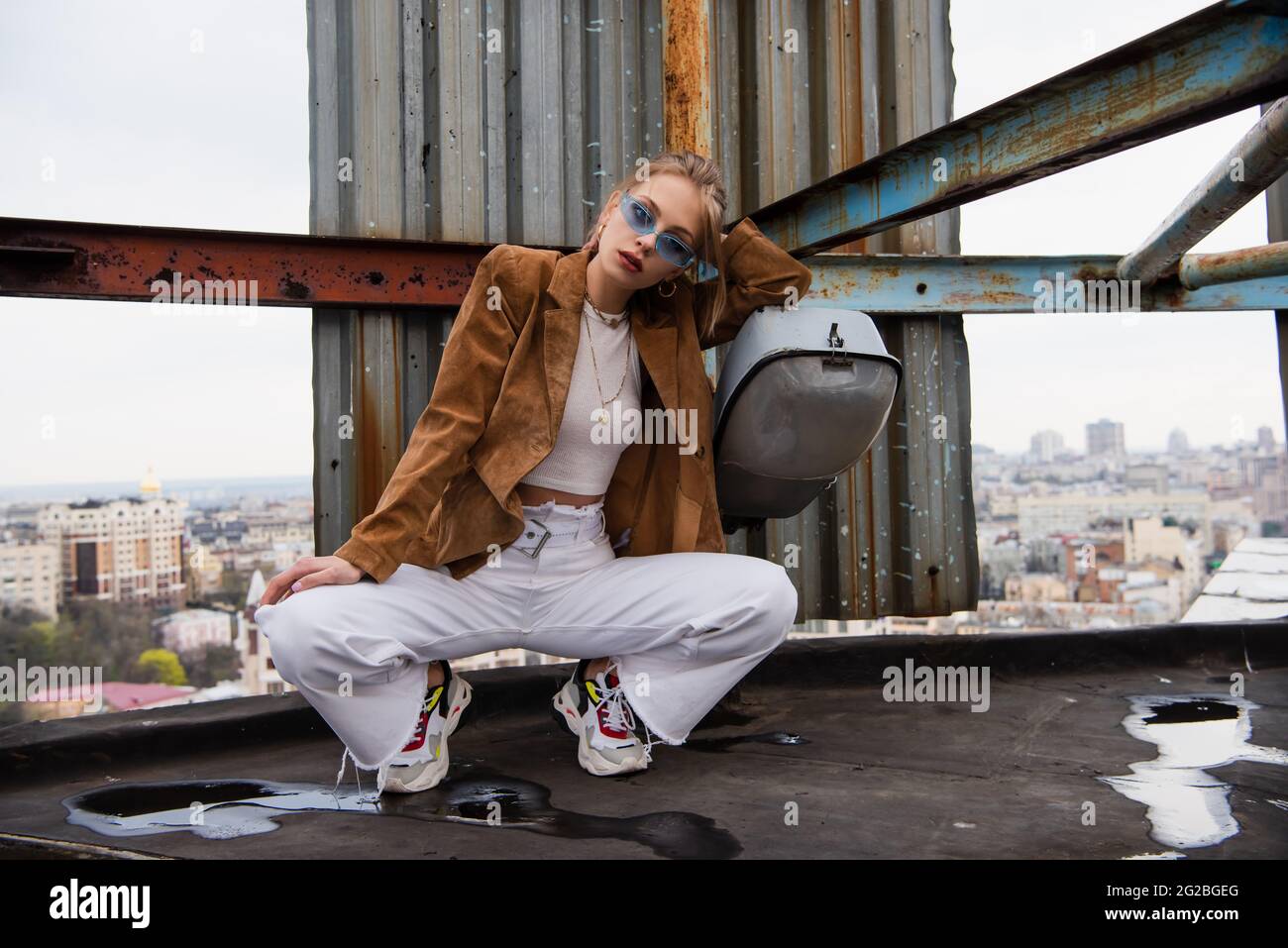 pretty young woman in blue sunglasses and trendy outfit sitting while ...