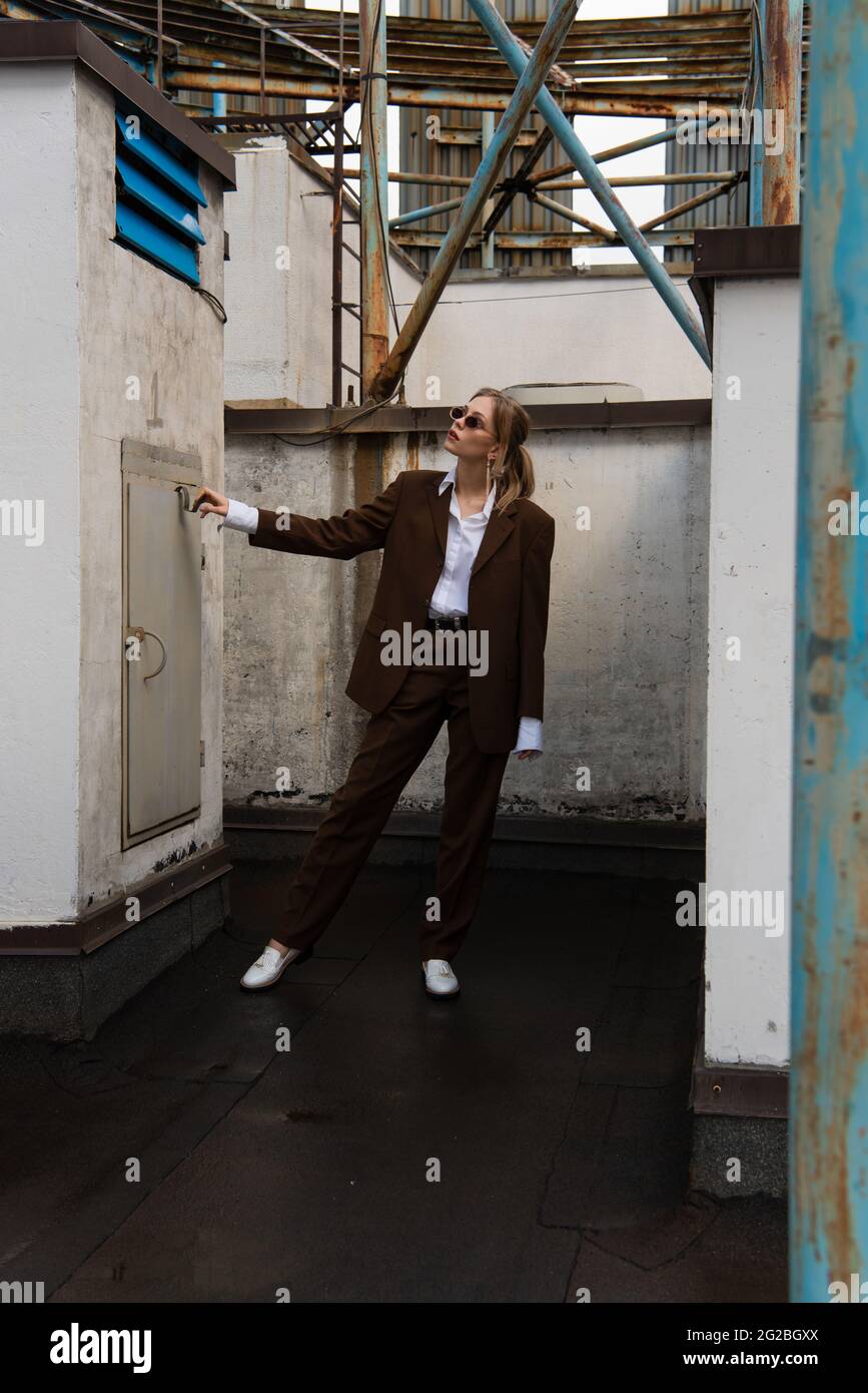 full length of trendy young model in sunglasses and suit posing on rooftop Stock Photo