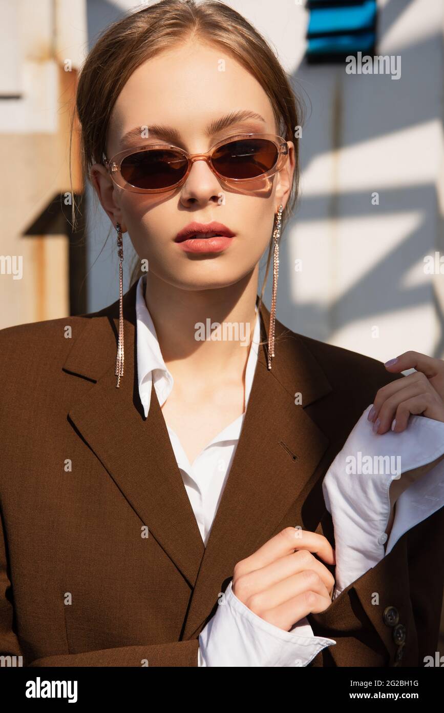 pretty young model with earrings in sunglasses posing on rooftop Stock Photo