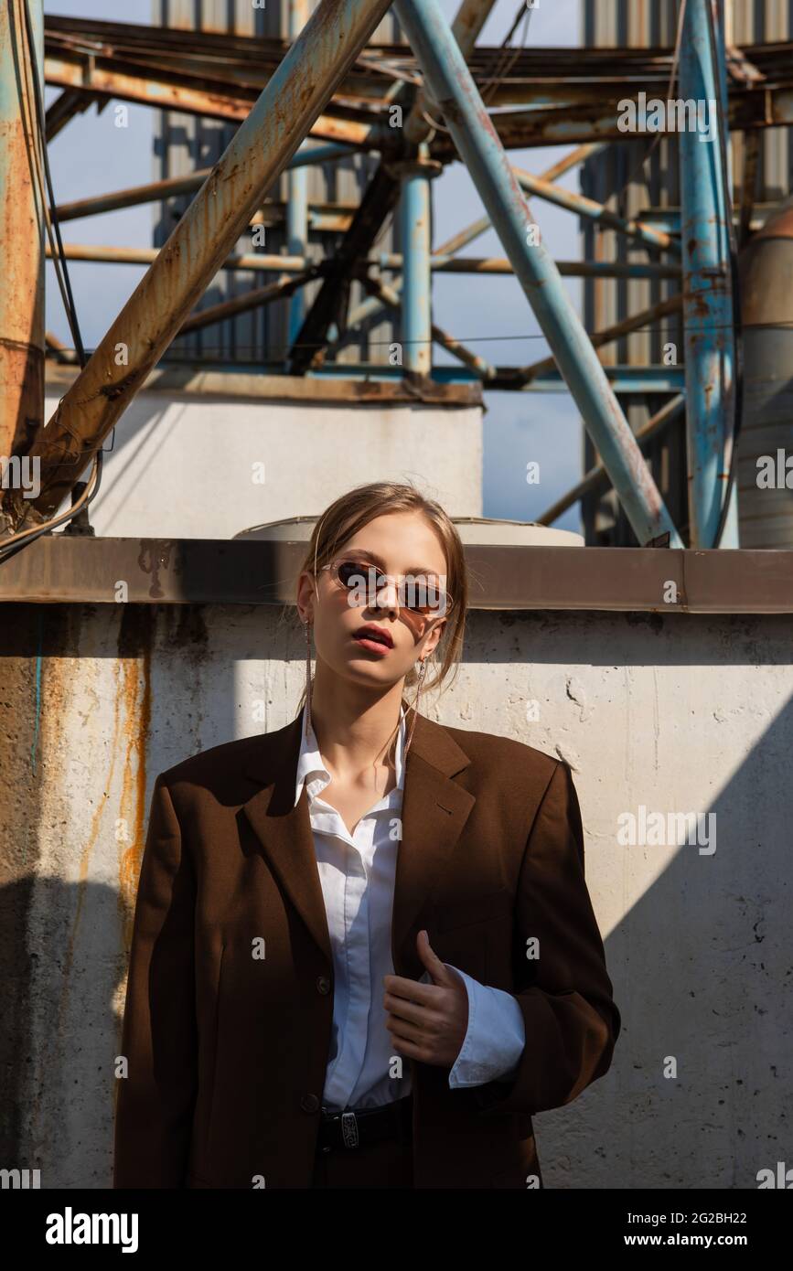 blonde young model in brown suit and sunglasses posing outside Stock Photo