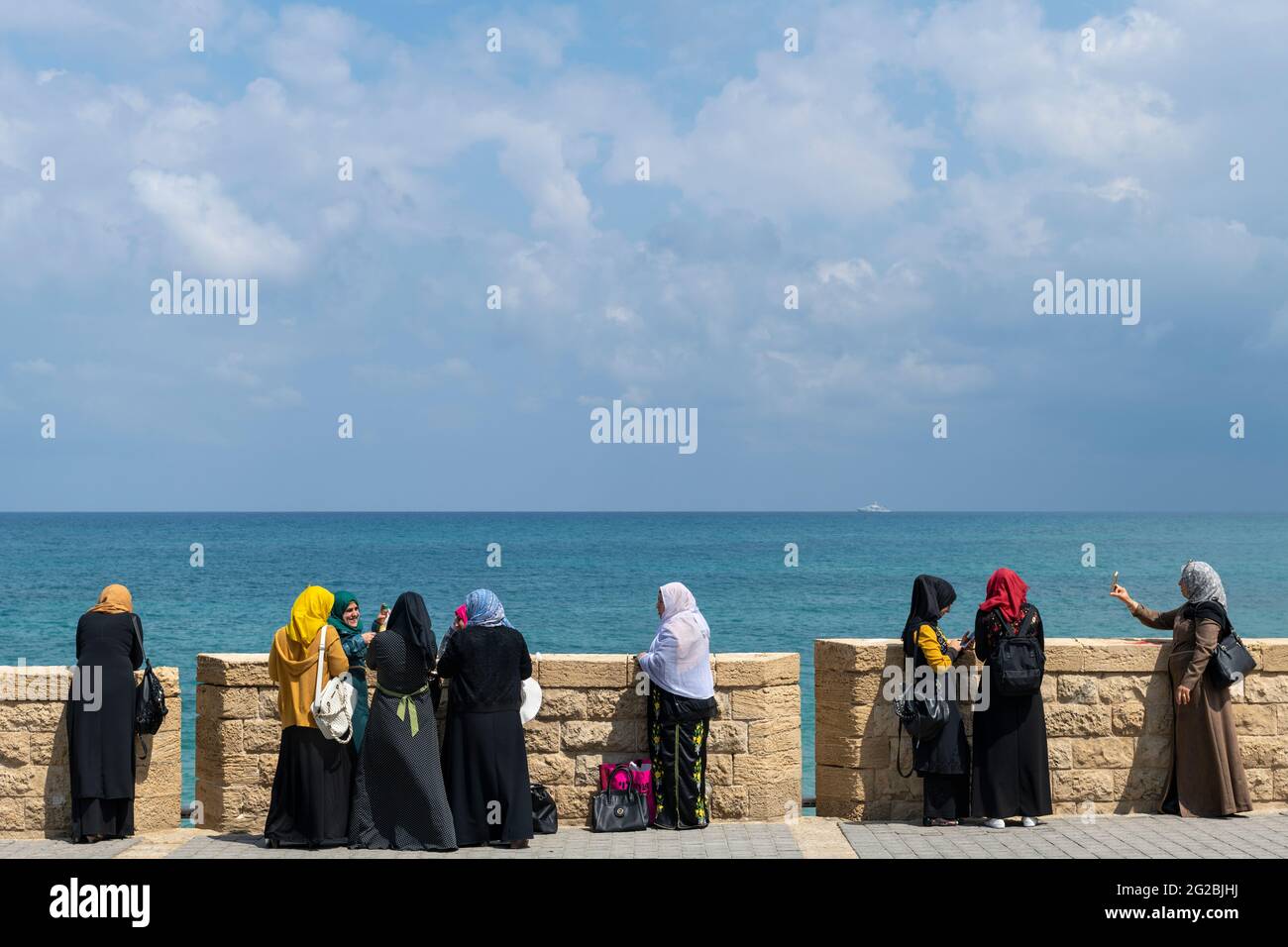 Muslim women wearing headscarf - hijab, enjoying on the beach, Jaffa. Tel Aviv. Religious garments have become more common among Muslims in Israel Stock Photo