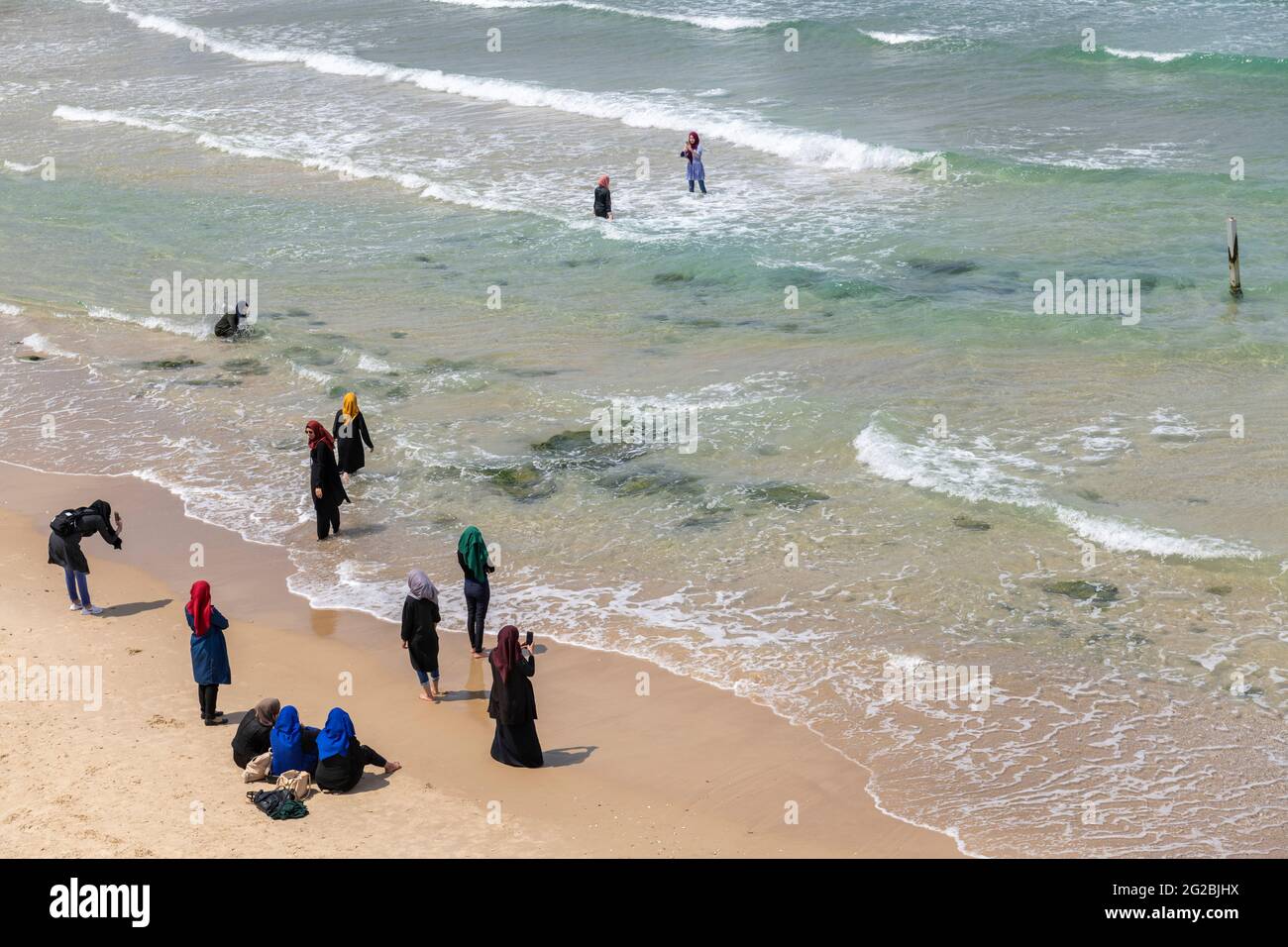 Muslim women wearing a headscarf - hijab, enjoying on the beach, Jaffa. Tel Aviv. Religious garments have become more common among Muslims in Israel Stock Photo