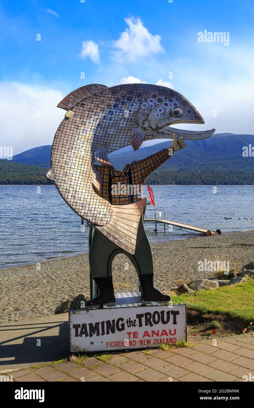 A 'Taming the Trout' photo cutout on the shore of Lake Te Anau, New Zealand, depicting a fisherman holding a giant fish Stock Photo
