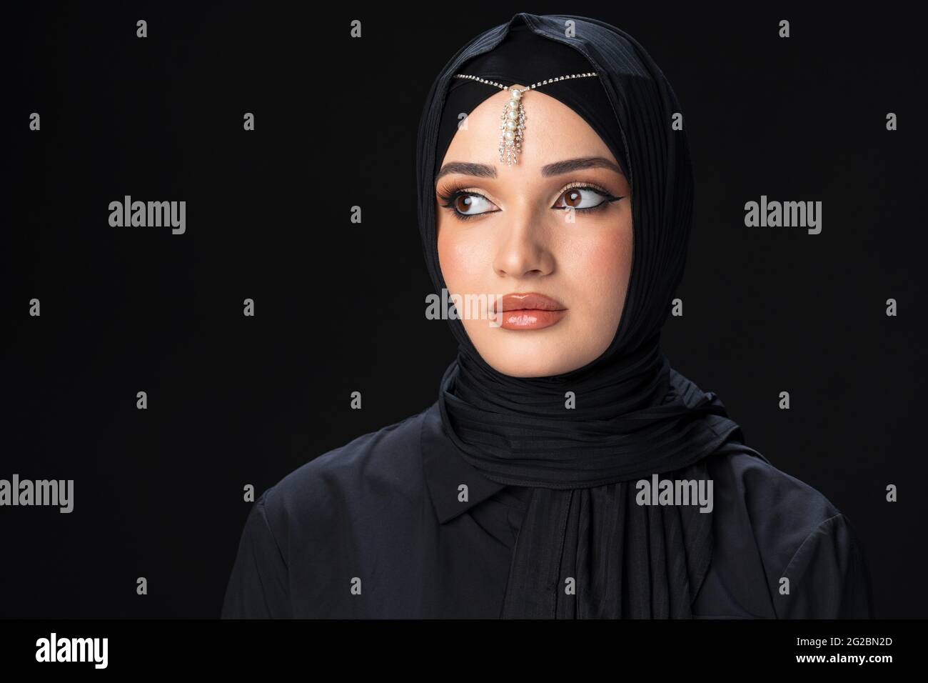 Portrait of a young muslim woman in hijab on black background Stock